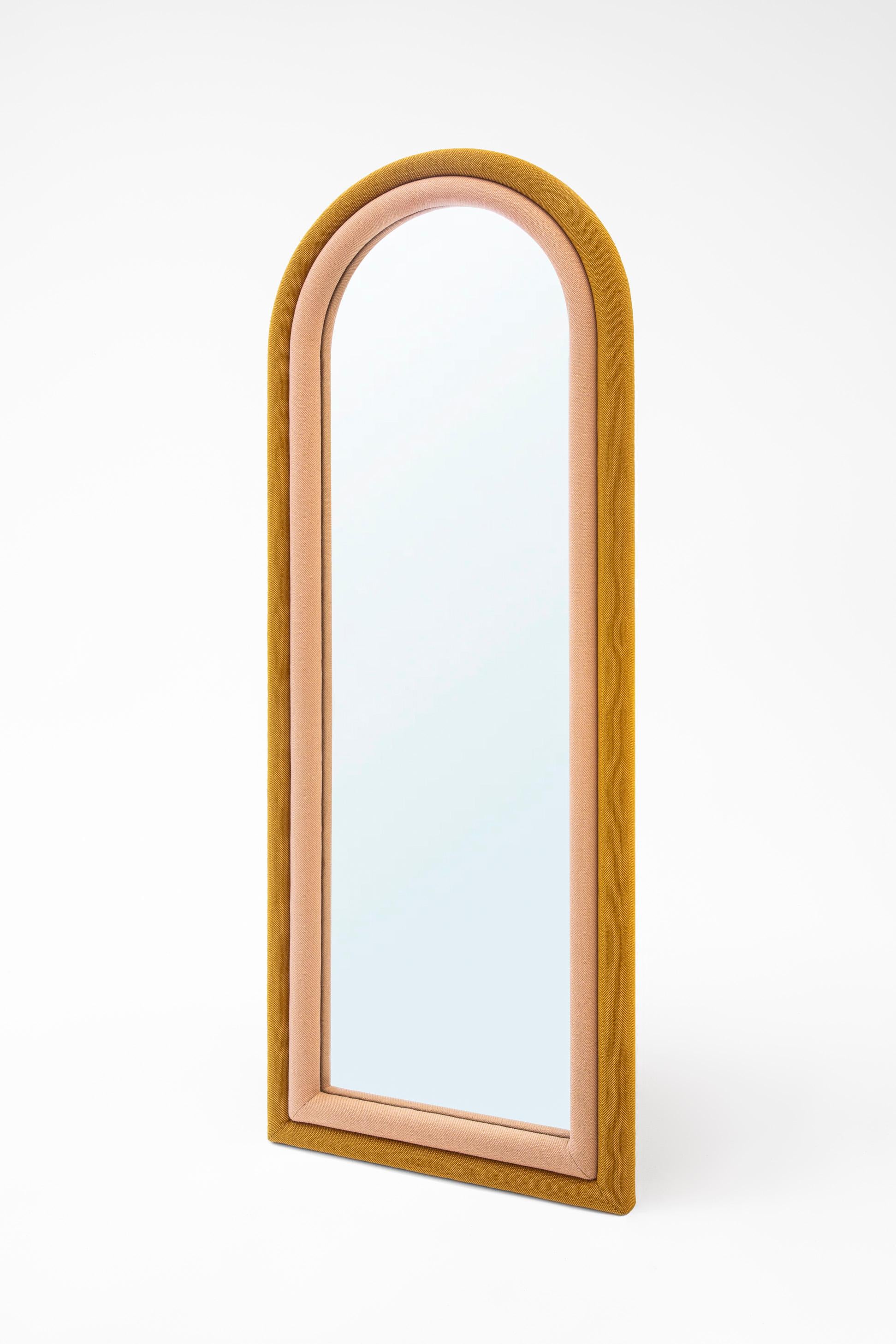 The floor version of the “Iris Mirror” has pink and mustard color upholstery wrapped around the arched shape. It can be hanged on the wall or stand by itself. It can be customized in fabrics and sizes as well.