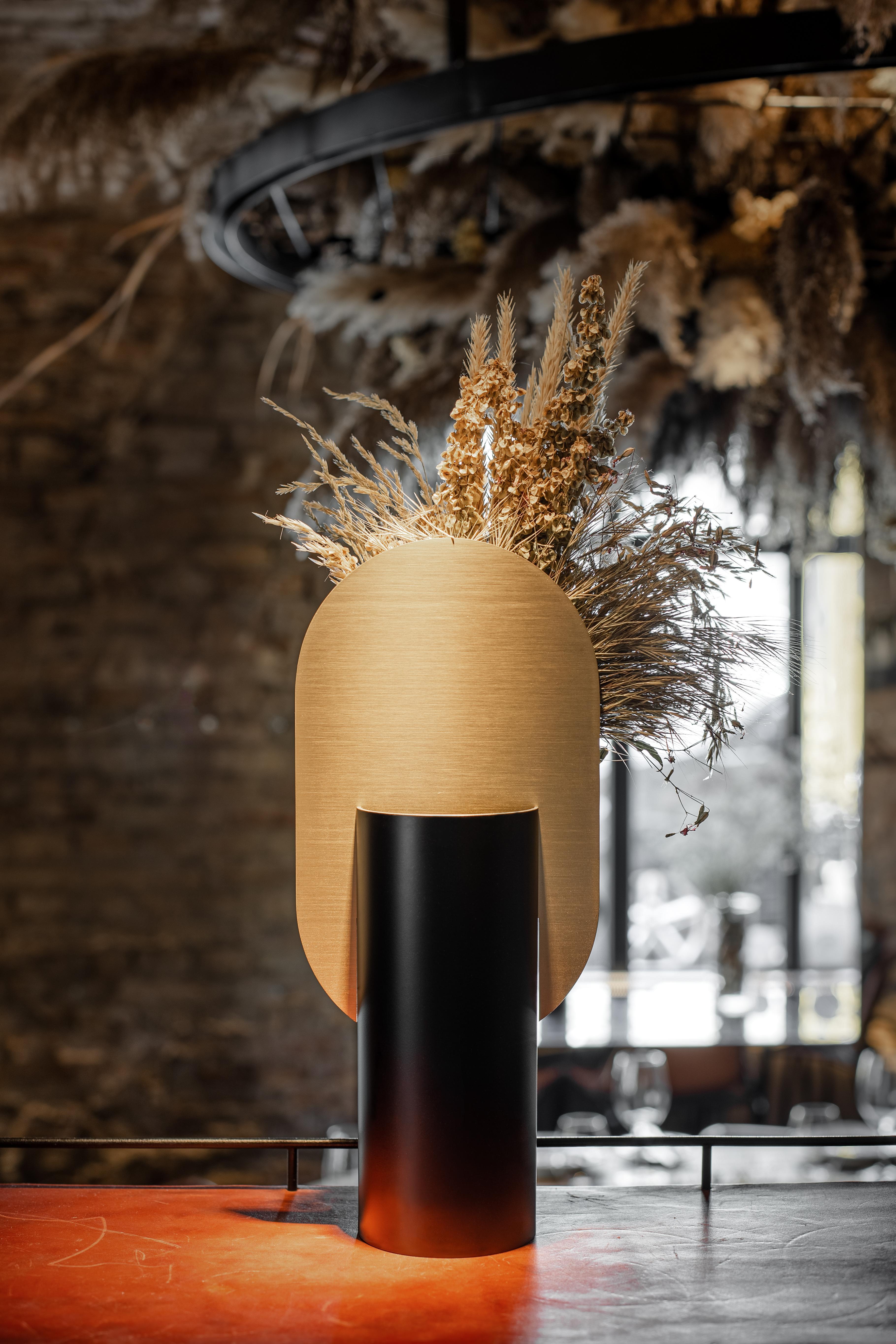 Vase Genke CS1 by Noom 

Brand: Noom
Designer: Kateryna Sokolova
Materials: Brass, painted steel
Color scheme: CS1 - black and brass
Dimensions: H 38 cm x W 17 cm x D 10 cm
Net Weight: 2 kg.

Genke vase, one of the vases from the 