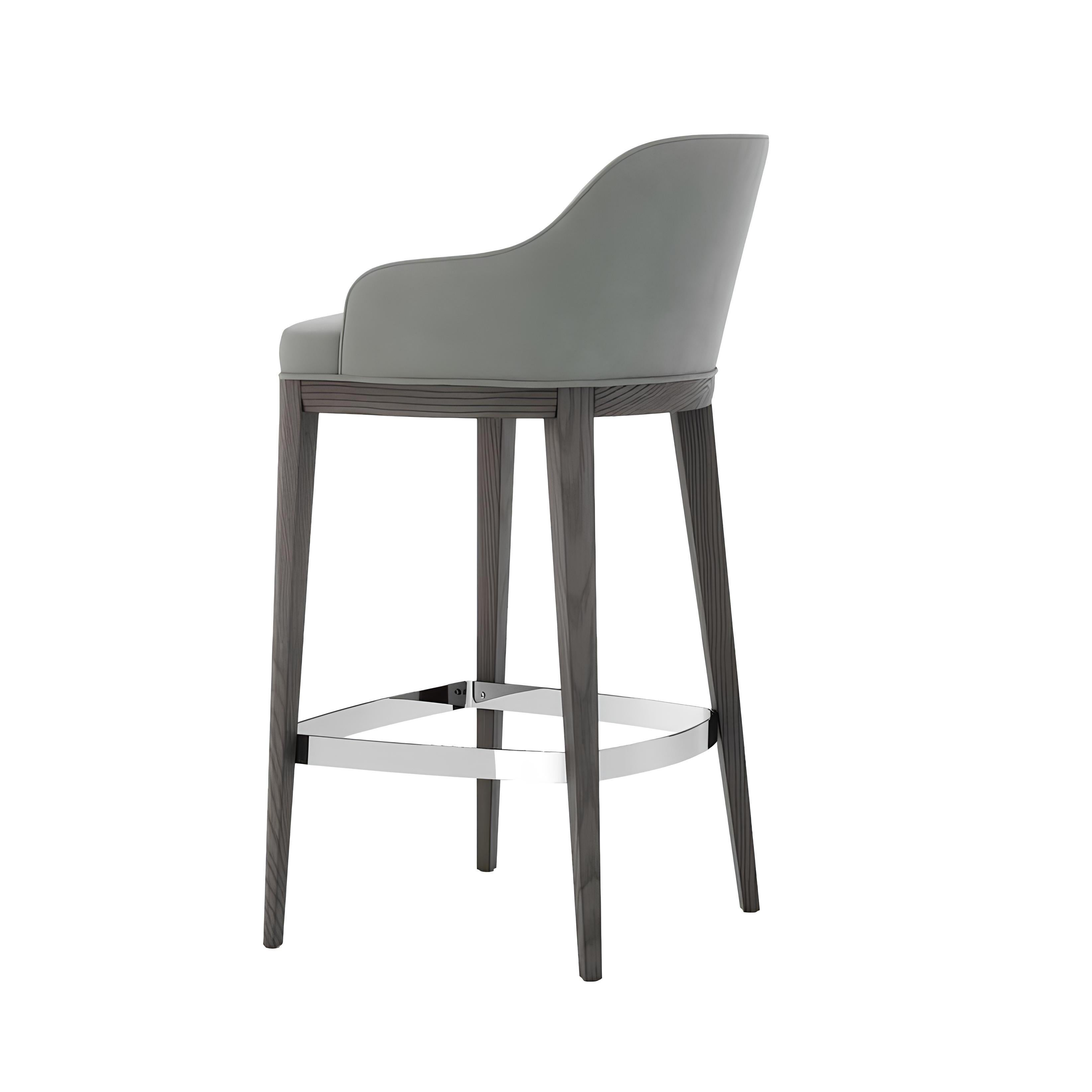 Experience a perfect fusion of design and comfort with this Barstool. This timeless piece, boasts a sophisticated upholstered seat and backrest that cradle you in exceptional comfort. A robust base paired with a metallic footrest ensures lasting