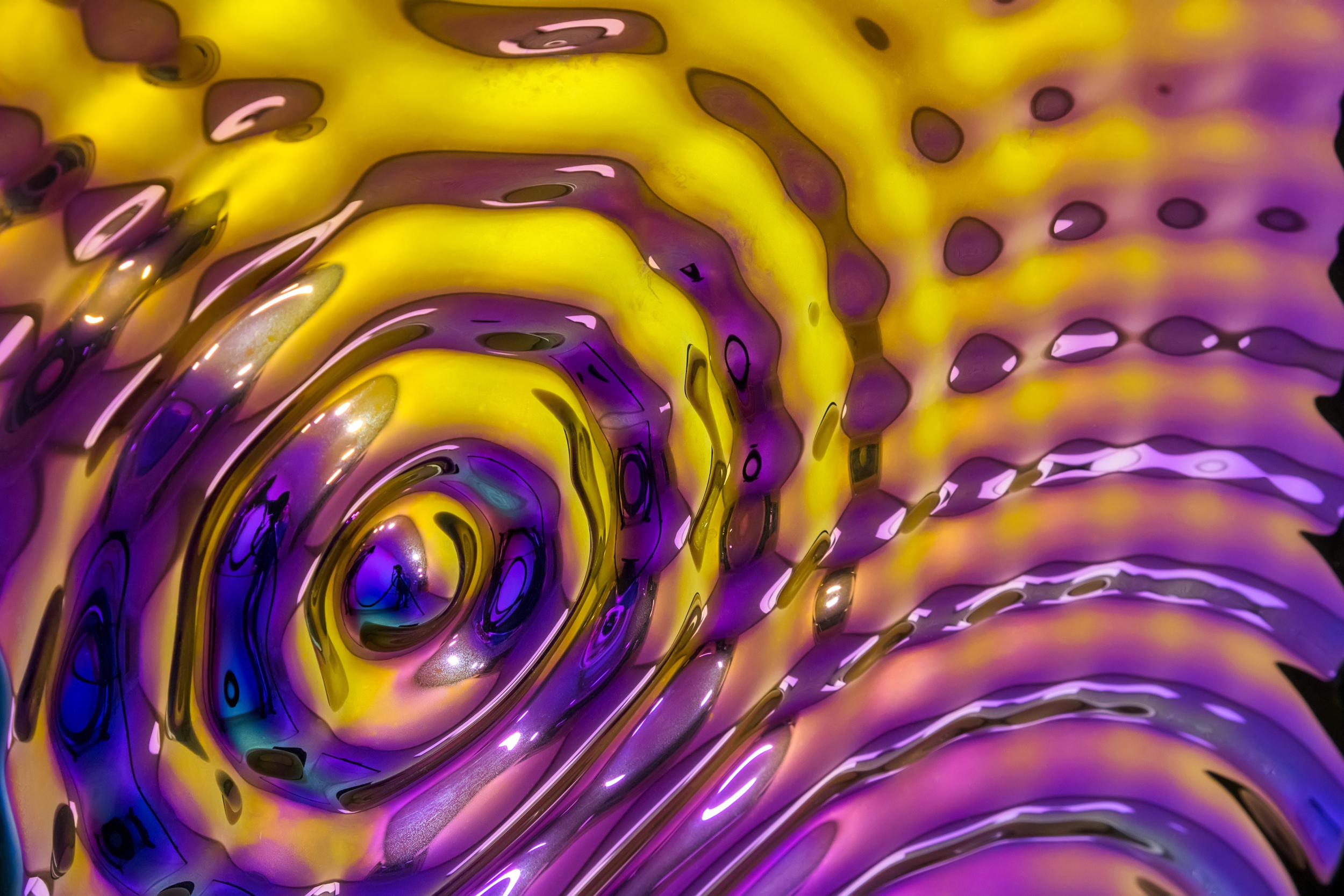 Fünf juwelenglänzende Tropfen unterbrechen ein Feld aus geriffeltem Glas und bilden ein kunstvolles rechteckiges Wandpaneel, das an Regen erinnert, der auf Wasser trifft. Die Rillen verstärken das Umgebungslicht, während die verschmolzenen Tröpfchen