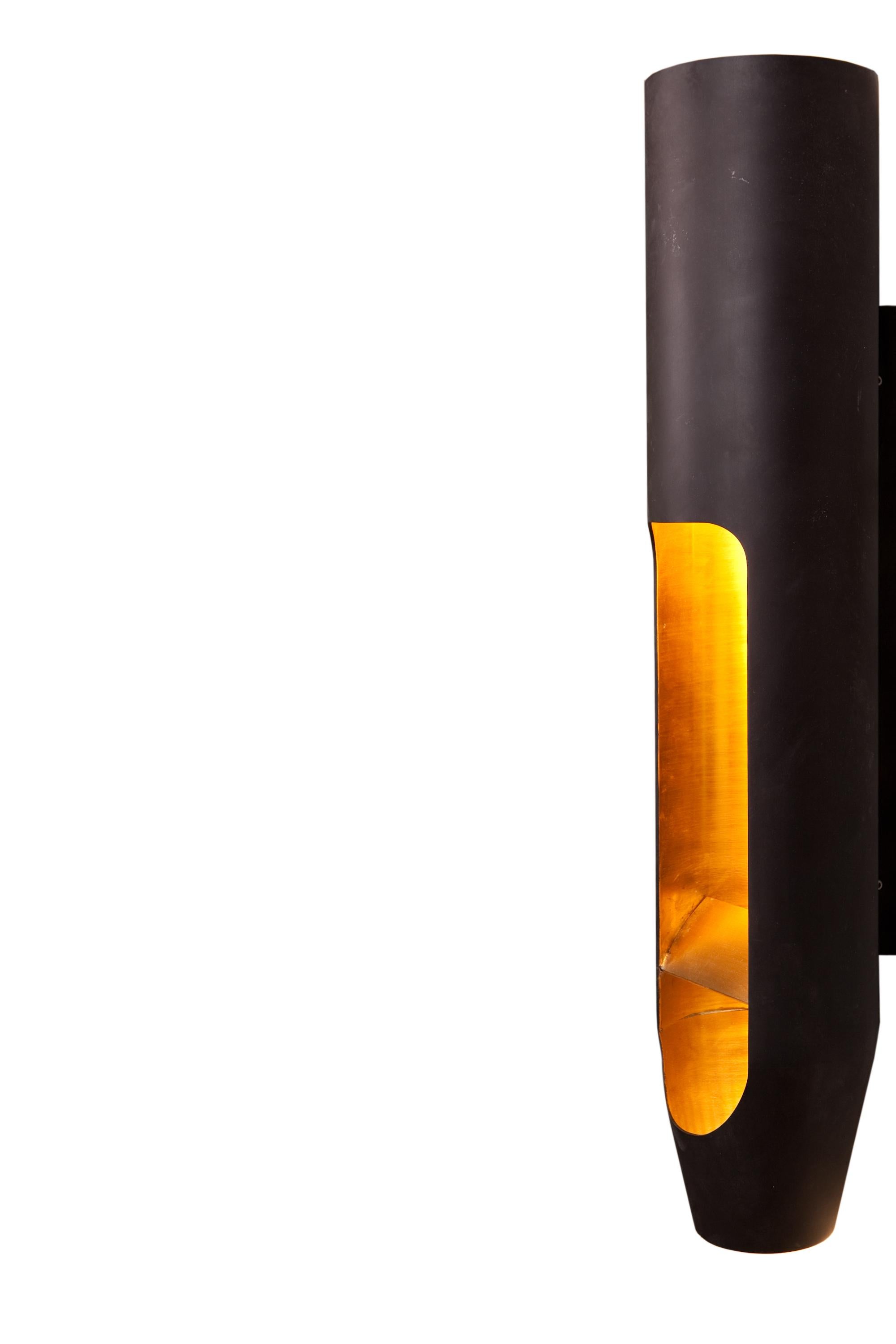 A wall fixture made of blackened brass in the form of an organ pipe. Outside black. Inside yellow brass. Above e27 lamp, at the bottom GU10 lamp. Or led.