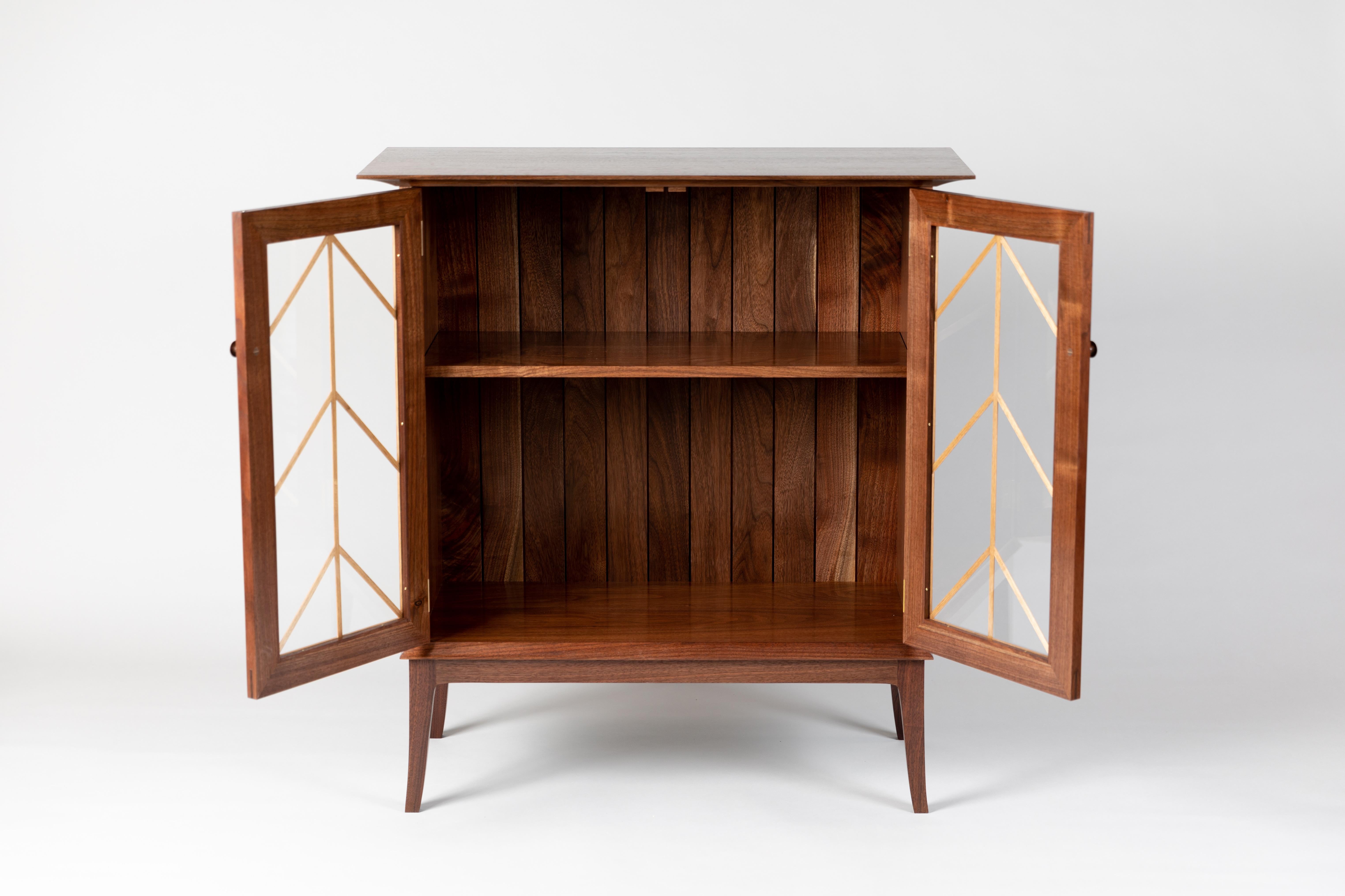 This cabinet is a clean, contemporary piece with traditional elements including a molding pattern unique to Meredith Hart Furniture over the glass doors. Designed to hold any variety of things without hiding them away such as small sculptures,