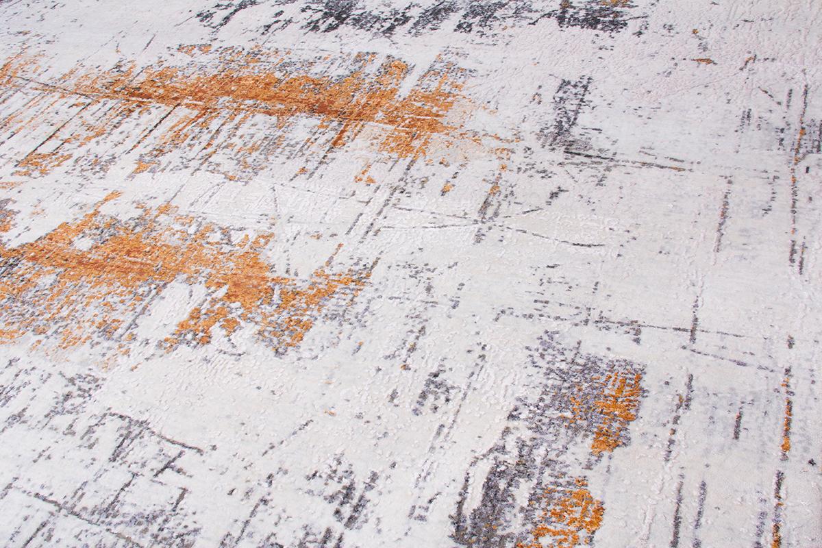 This contemporary piece from Rug & Kilim has a modern take on an abstract rug design. Originating from India, the very placid ivory white and gray field is accented by textural patterns of orange-gold and black, hand knotted in durable high-quality