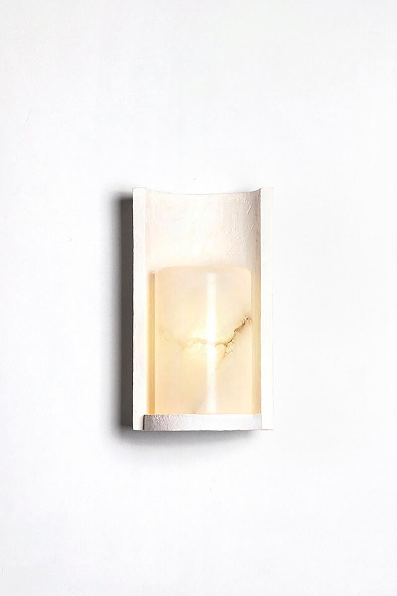Sconce in white plaster and alabaster. 

Reinterpretation of torchere classical light, CYRUS sconce is made up of a plaster shell holding an alabaster shape.
Available in bronze and alabaster version under the name THEA.

Designer: Garnier &
