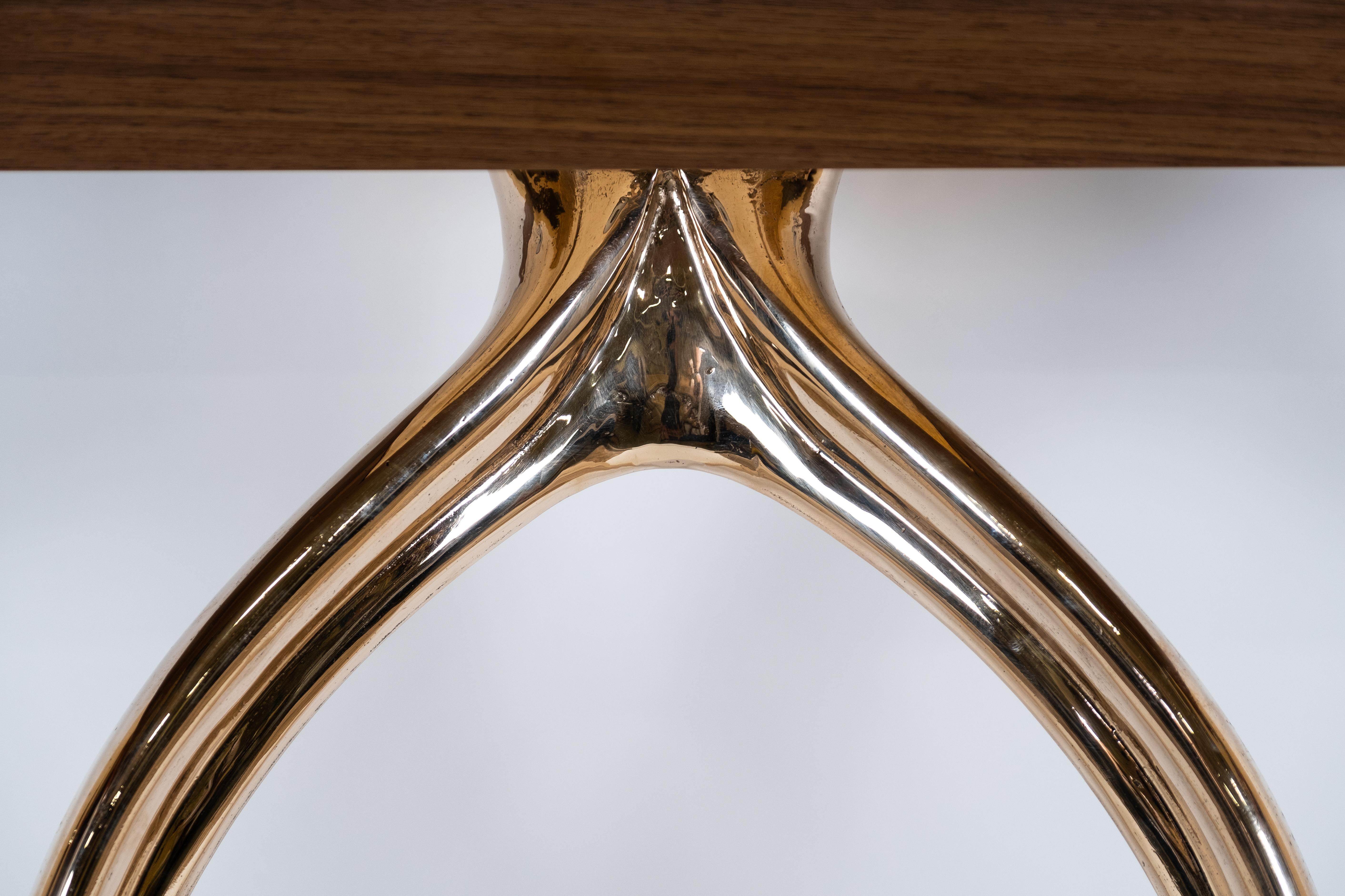 A single cast-metal Wishbone leg is paired with a demilune or rectangular tabletop of domestic hardwood. The sand-casting process produces faintly perceptible irregularities that enhance the leg’s tactile appeal. The wood top has STACKLAB’s