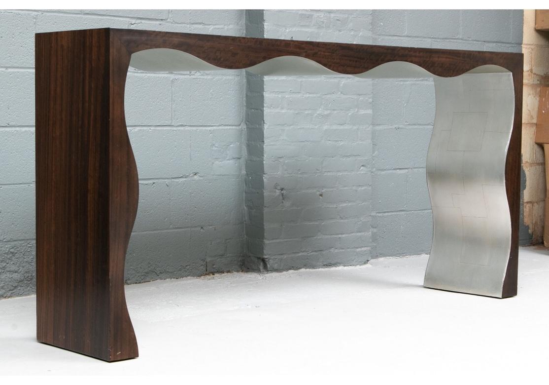 Scalloped shape in variegated laminated exotic wood on the top and sides. Natural dark stained wood on the frieze and fronts of the supports. Unexpected silvered surfaces on the insides of the supports with linear markings.
Measures: Length 74