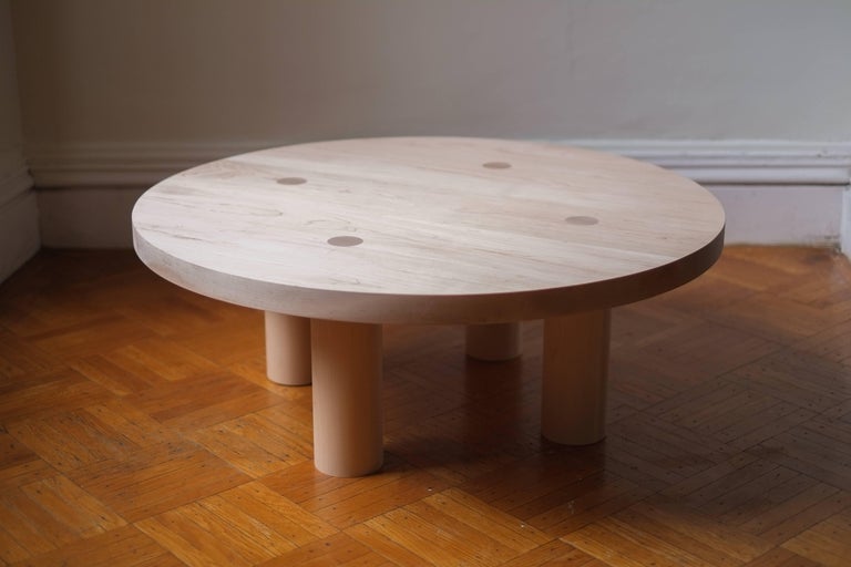 This contemporary, minimal wooden coffee table features four large round legs that pierce the 2 inch thick top to reveal the joinery and remove the need for any other structural components. This detail communicates its solid construction, while