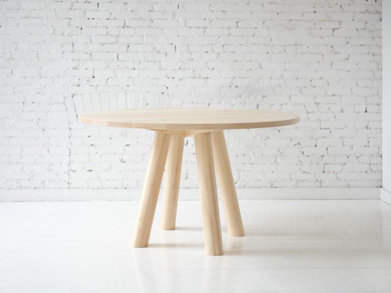 This contemporary, minimal dining table features large diameter round legs and bold trestle supports to give rise to a stone or hardwood top. The table top features a wood surface detail that centers the top to the base and communicates the