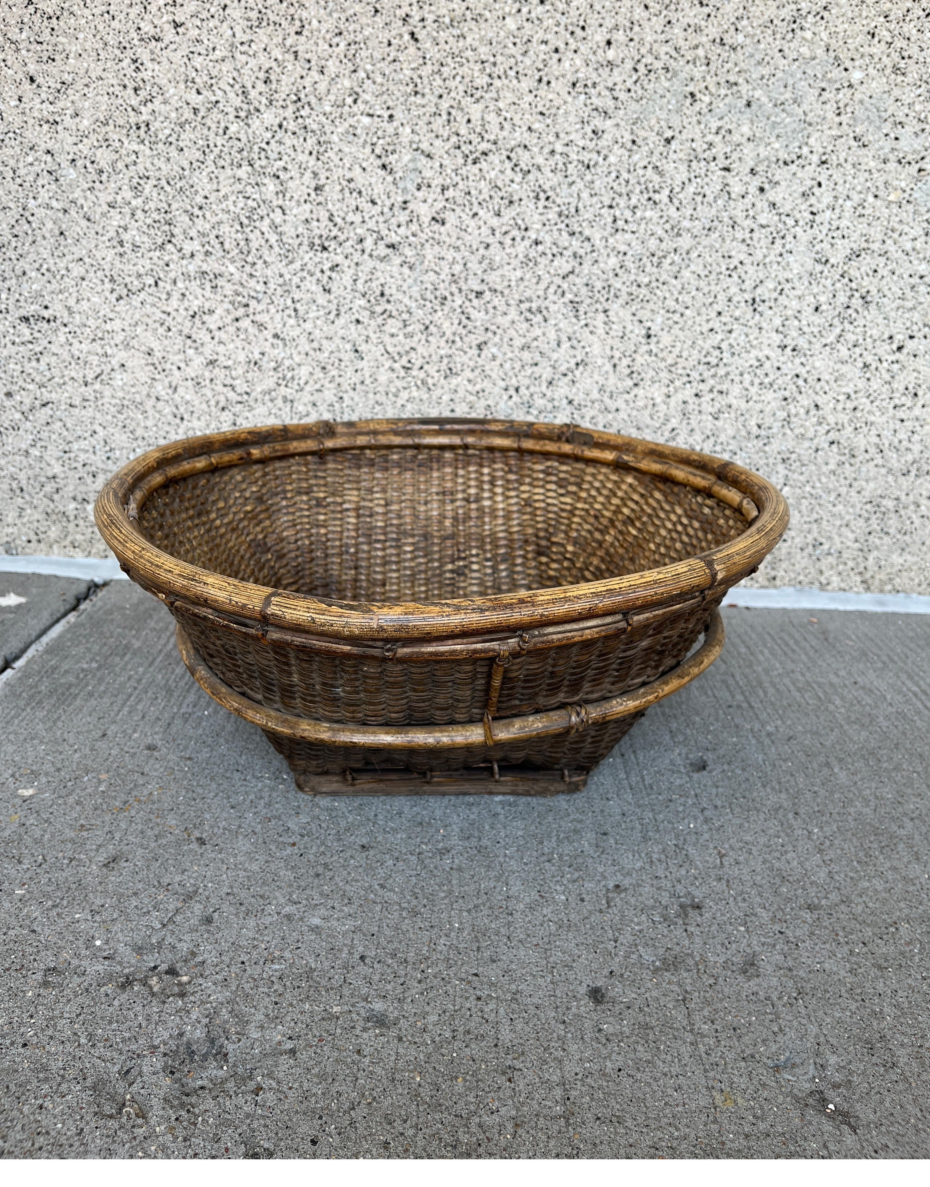 A distinctly shaped and tightly woven natural fiber and wood basket. A perfect centerpiece, this hand made and expertly assembled basket can be used in a wide variety of settings. The basket's somewhat irregular shape and combination of home grown