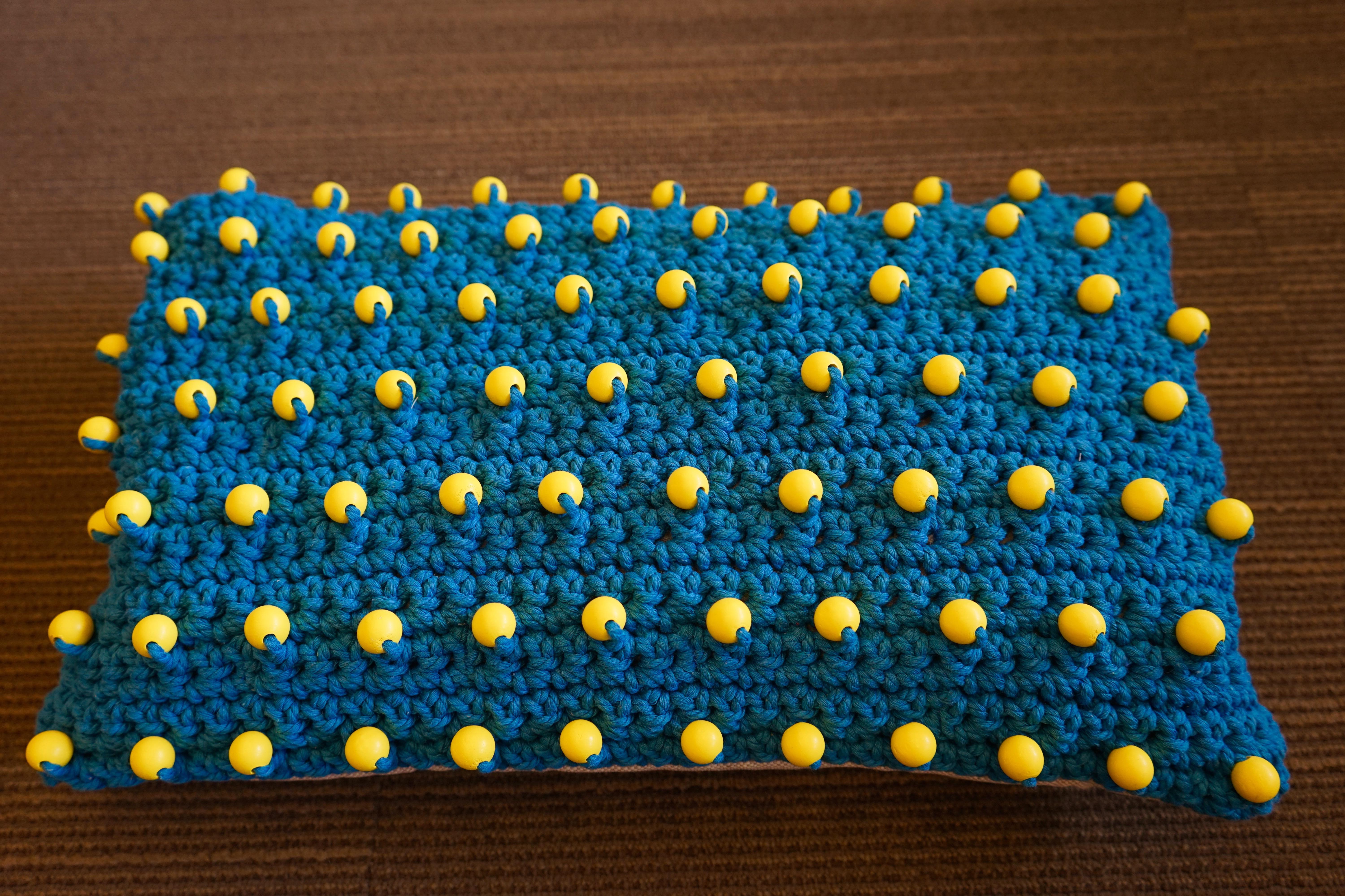Contemporary woven blue pillow with bright yellow beads.
