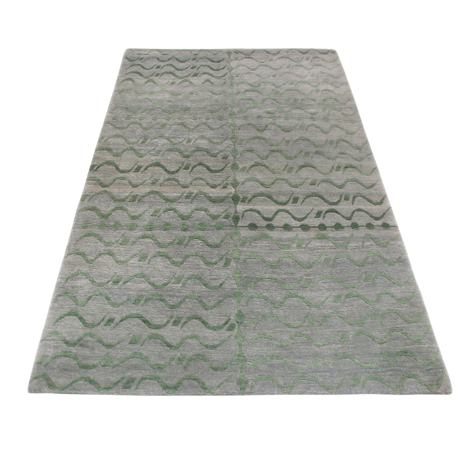 Rug & Kilim’s Youngste design originates from Nepal, hand knotted in high-quality wool with a paneled all-over field design. The particularly luminous, borderless lengths of deep green pair elegantly with the more industrial, abrashed silver-gray