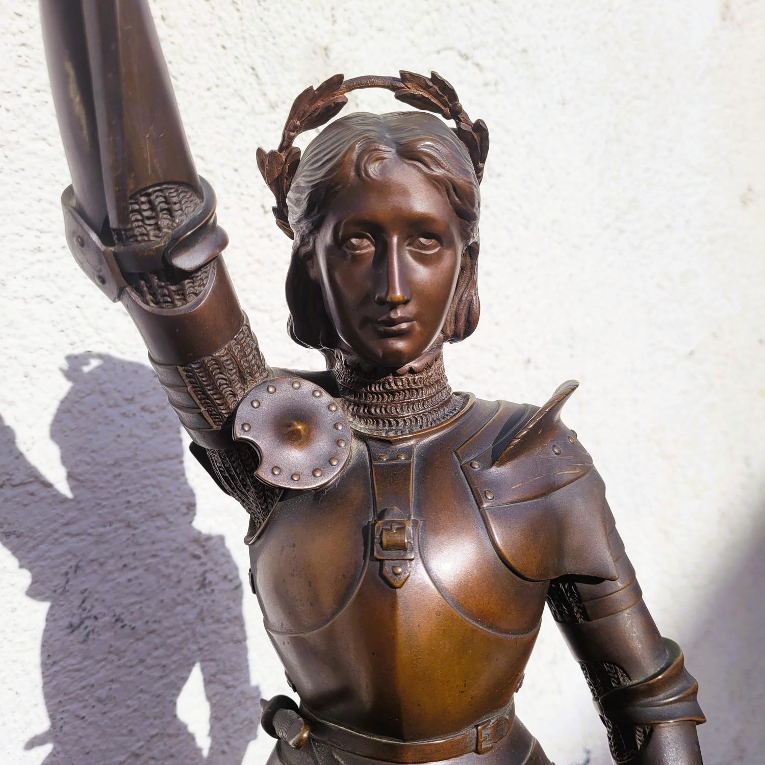 Patinated bronze sculpture representing Joan of Arc in armor, brandishing her sword  

Sculpture signed Contenot on the base (Henri Daniel)  

Joan is a young French woman of peasant origin; in 1429, she claims to have received a visit from saints,