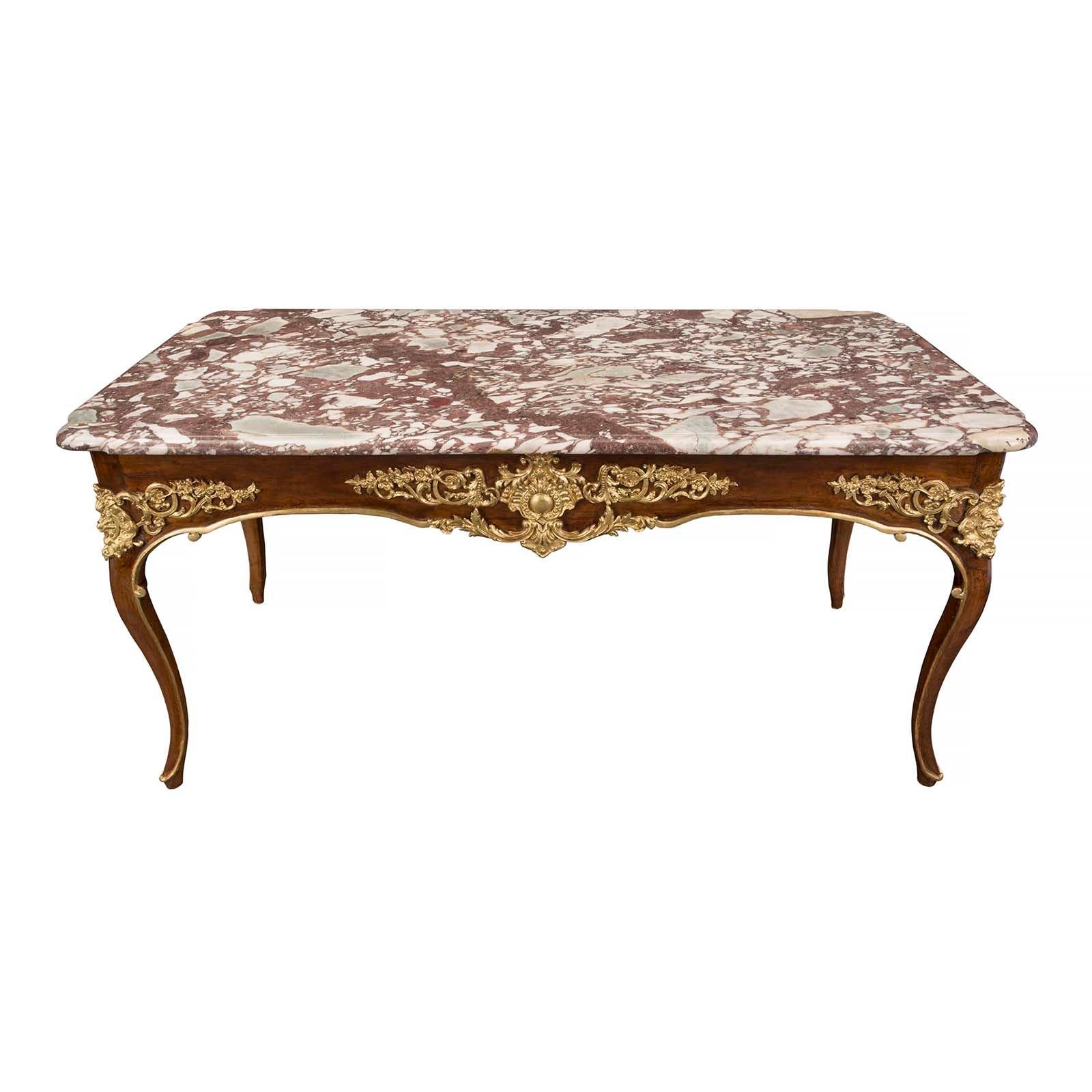 An impressive Continental 18th Century Louis XV period walnut, giltwood and marble rectangular center table. The table is raised by elegant cabriole legs with a fine giltwood filet which extends along the border of each leg and across the arbalest