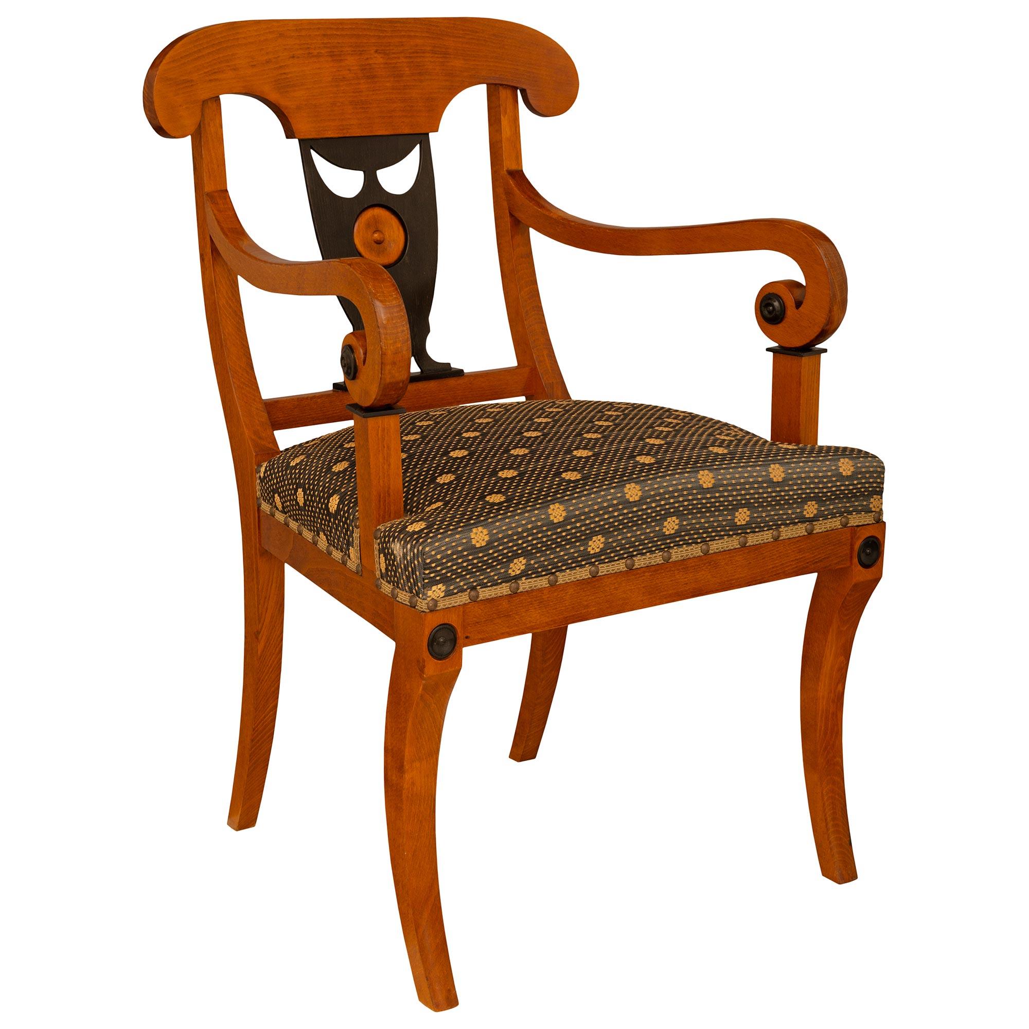 A handsome Continental 19th century Biedermeier st. Fruitwood and ebonized Fruitwood armchair. The armchair is raised by four gently curved square legs below the straight front apron which is flanked by circular ebonized Fruitwood accents. The