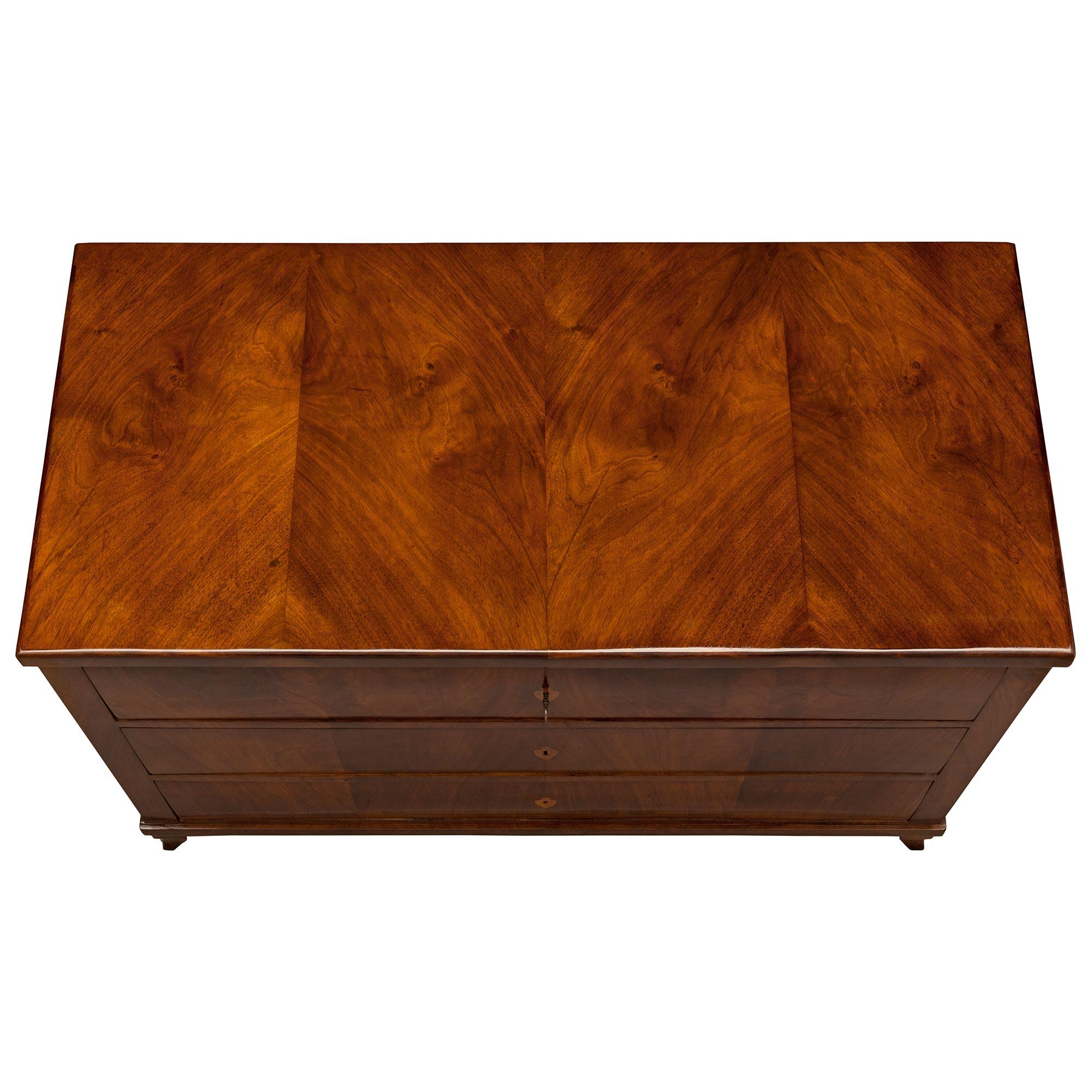 A handsome and most elegant Continental 19th century Biedermeier st. Walnut chest circa 1840. The three drawer chest is raised by elegant scrolled tapered feet below the straight apron. Each of the three drawers showcases the stunning butterfly