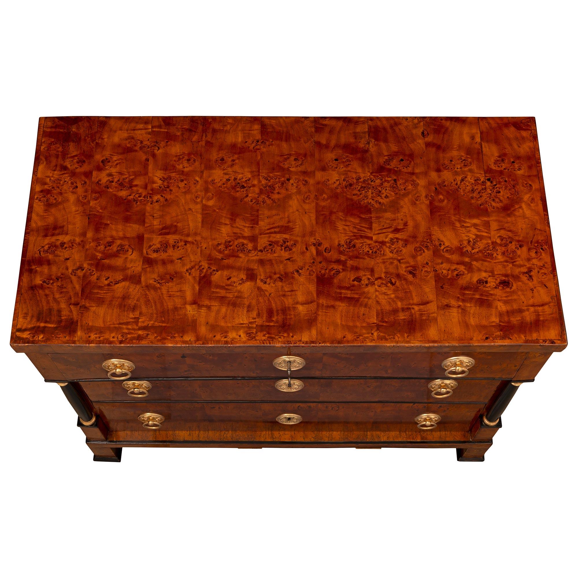 A stunning and most decorative Continental 19th century burl Birchwood, ebonized Fruitwood, and ormolu commode. The three-drawer chest is raised by elegant block legs with fine mottled feet. Above the straight frieze are the three drawers each