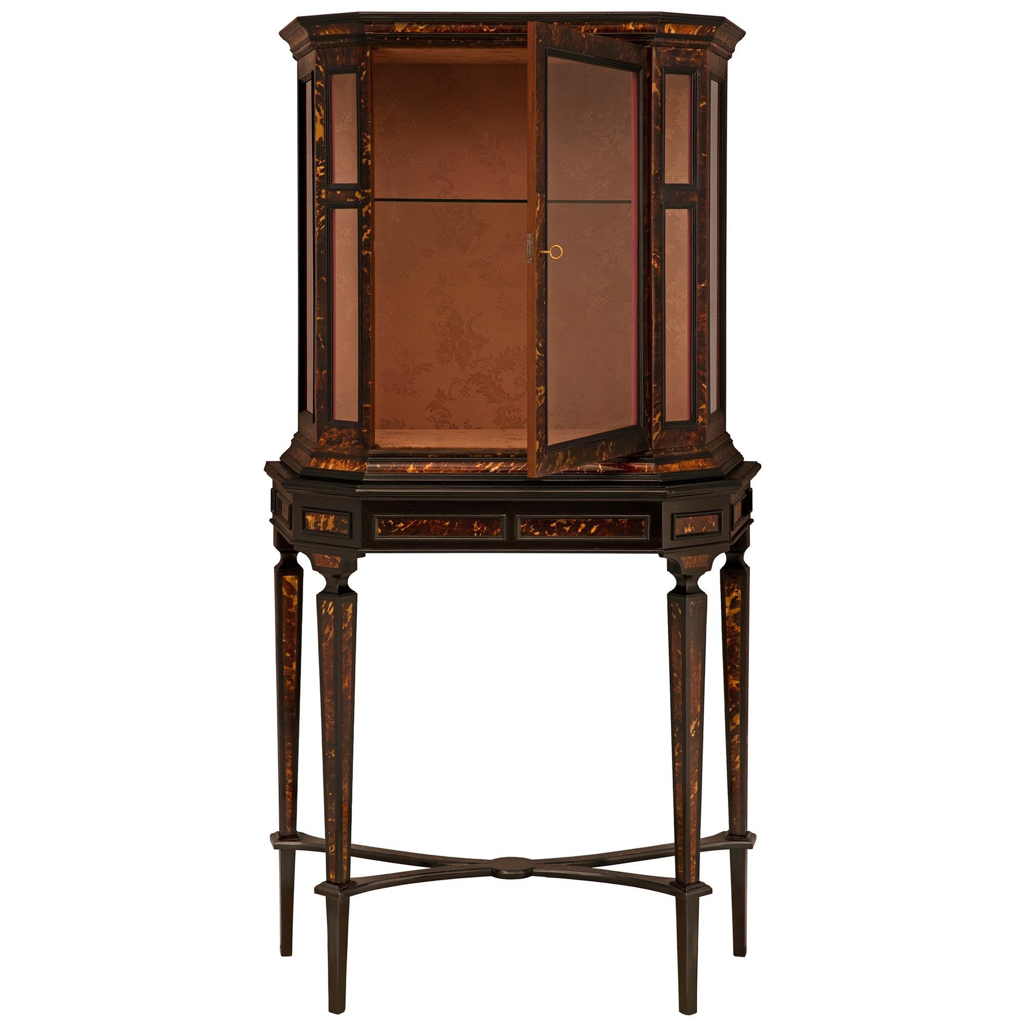 A very handsome and elegant Continental 19th century ebonized Fruitwood and Tortoiseshell cabinet vitrine. This beautiful freestanding vitrine is raised by four slender square tapered legs decorated by Tortoiseshell on all sides. Each leg is