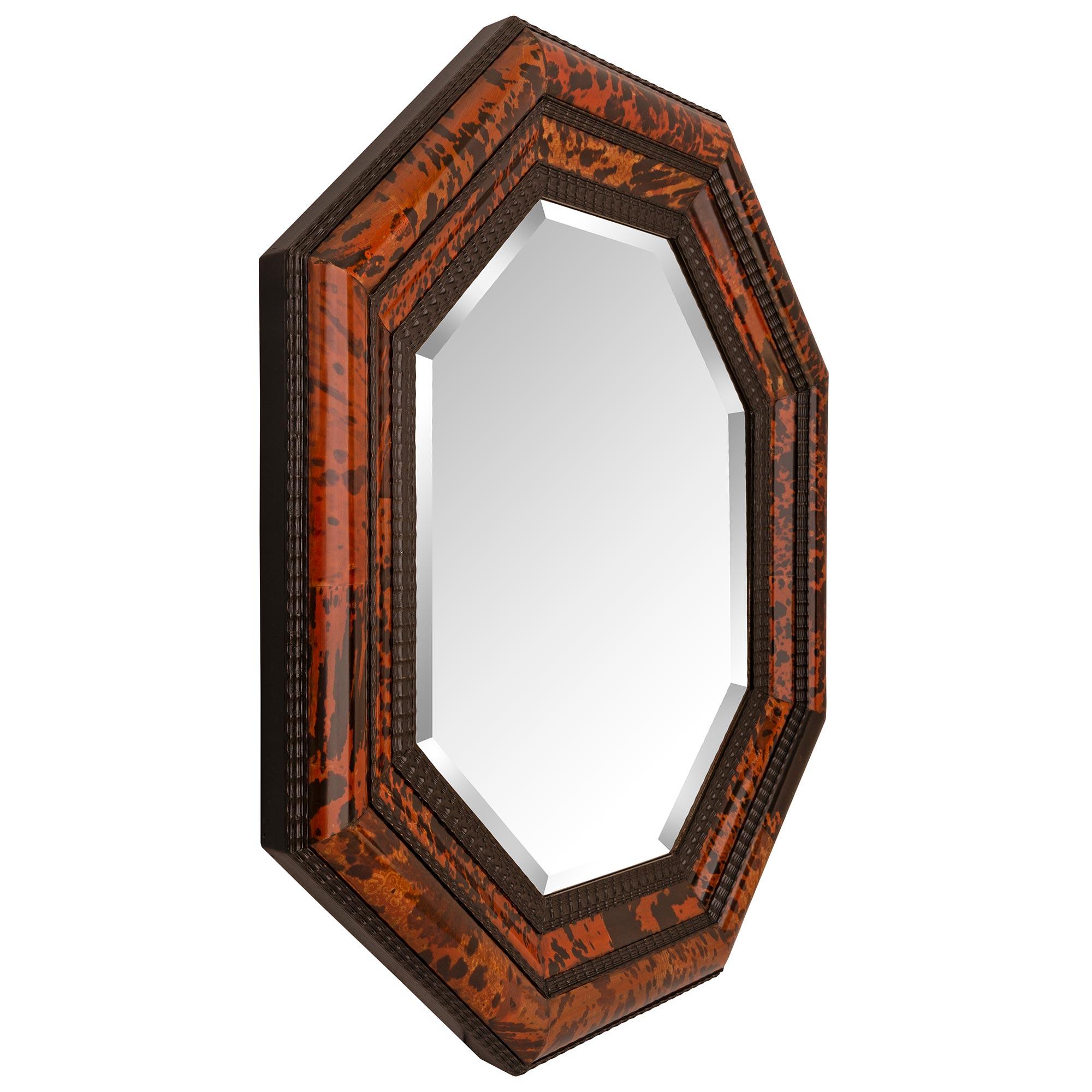 A stunning and most decorative Continental 19th century ebonized Fruitwood and Tortoiseshell mirror. The octagonal shaped mirror retains its original beautiful beveled mirror plate set within a striking mottled wavy designed wrap around band and
