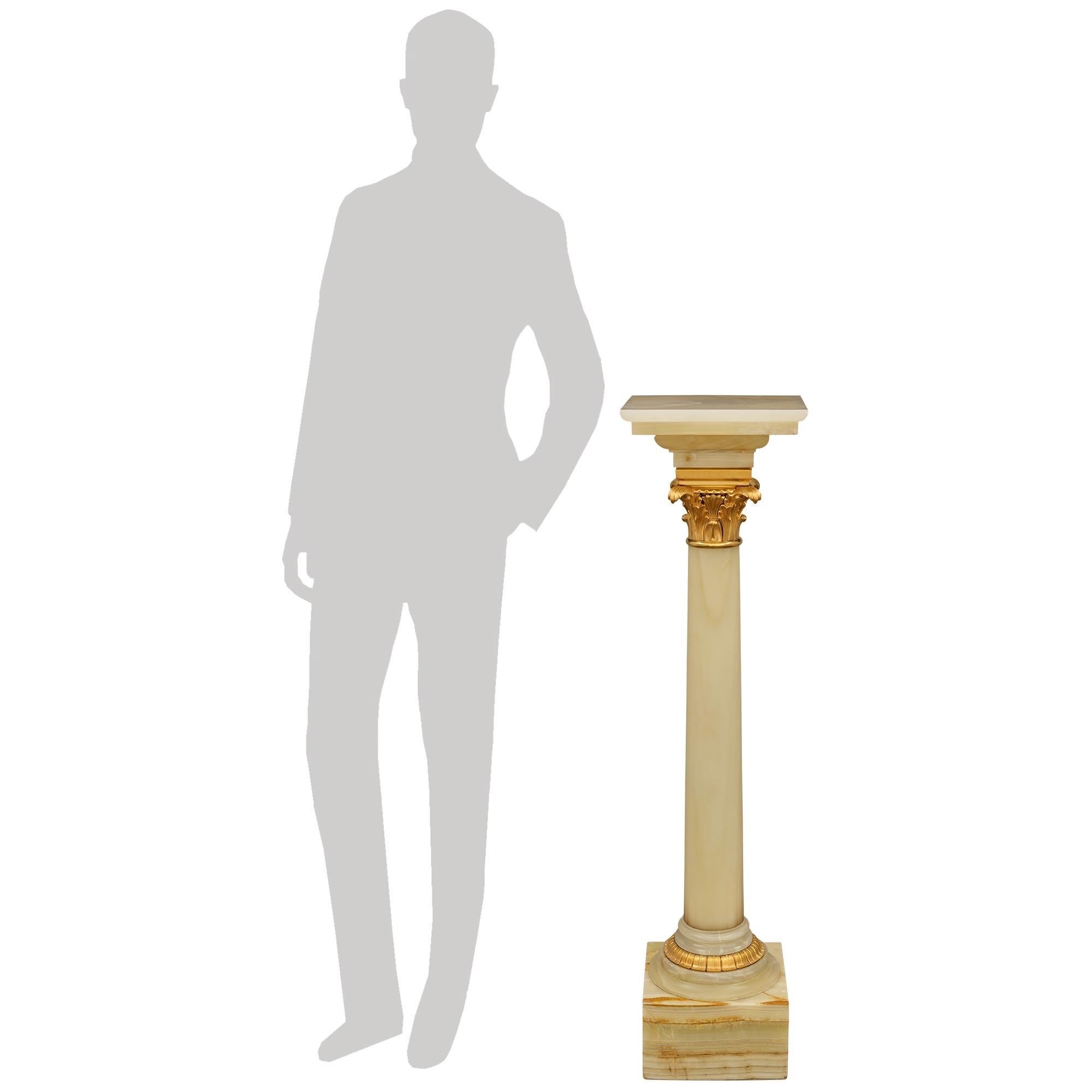 Un elegante e decoratissimo piedistallo neoclassico del XIX secolo. Piedistallo/colonna in onice e ormolu. La bella colonna in onice verde è sollevata da un blocco quadrato al di sotto di una base circolare screziata, ornata da una fascia centrale