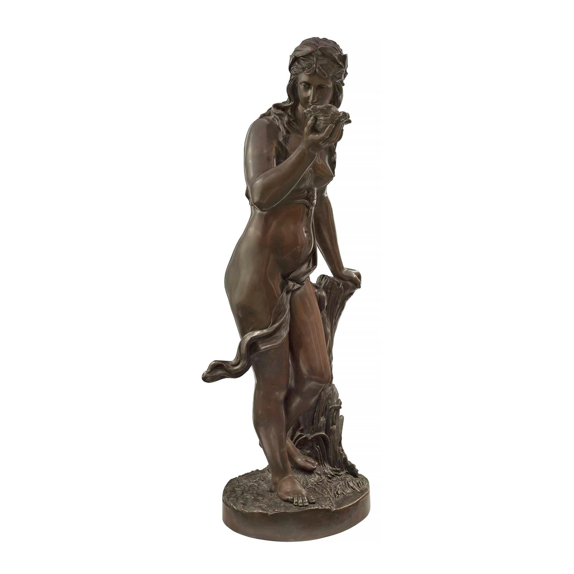 A high quality Continental 19th century patinated bronze statue of a beautiful maiden holding a seashell signed Schnider. The Bronze is raised by a circular base with a grass like design and a detailed tree truck. The wonderfully beautiful maiden