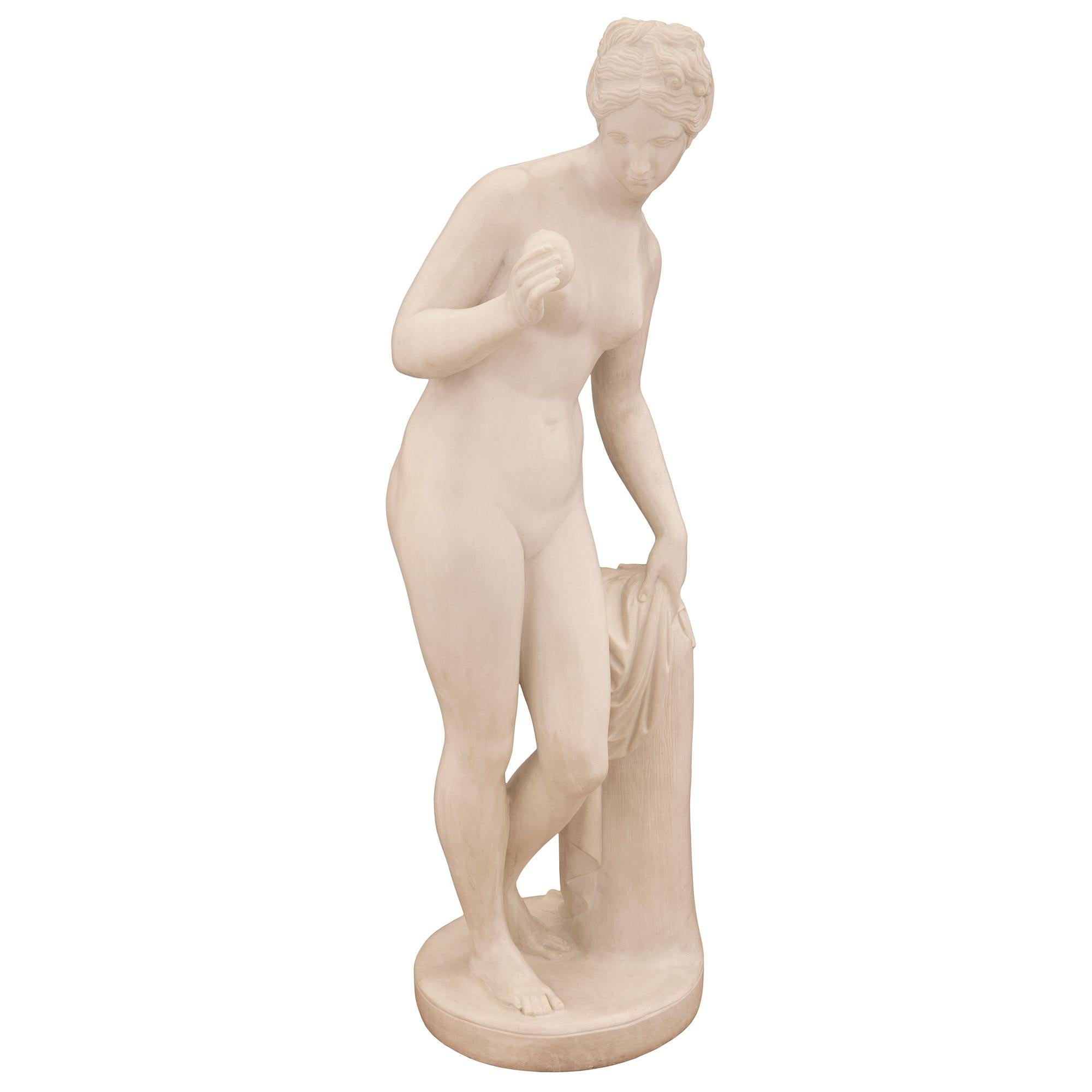 A beautiful Continental 19th century white Carrara marble statue of Venus after a model by Bertel Thorvaldsen. The striking statue is raised by a circular base where Venus stands next to a tree stump draped in a finely sculpted flowing fabric. Venus