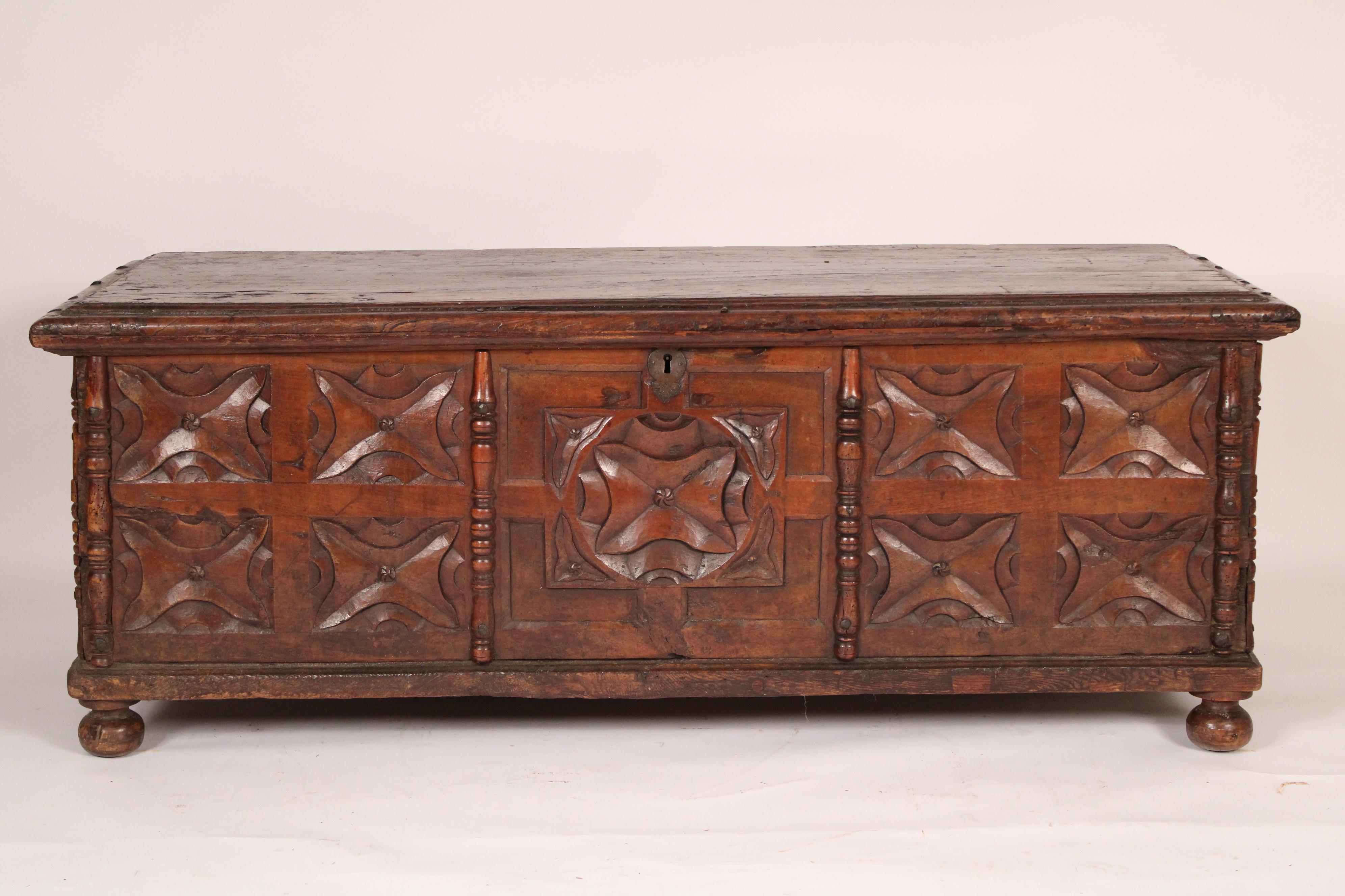 Continental baroque style oak trunk, circa early 19th century. With a single board rectangular overhanging top with molded front and side edges, the front with a central carved panel flanked by 4 carved panels on either side, resting on later bun