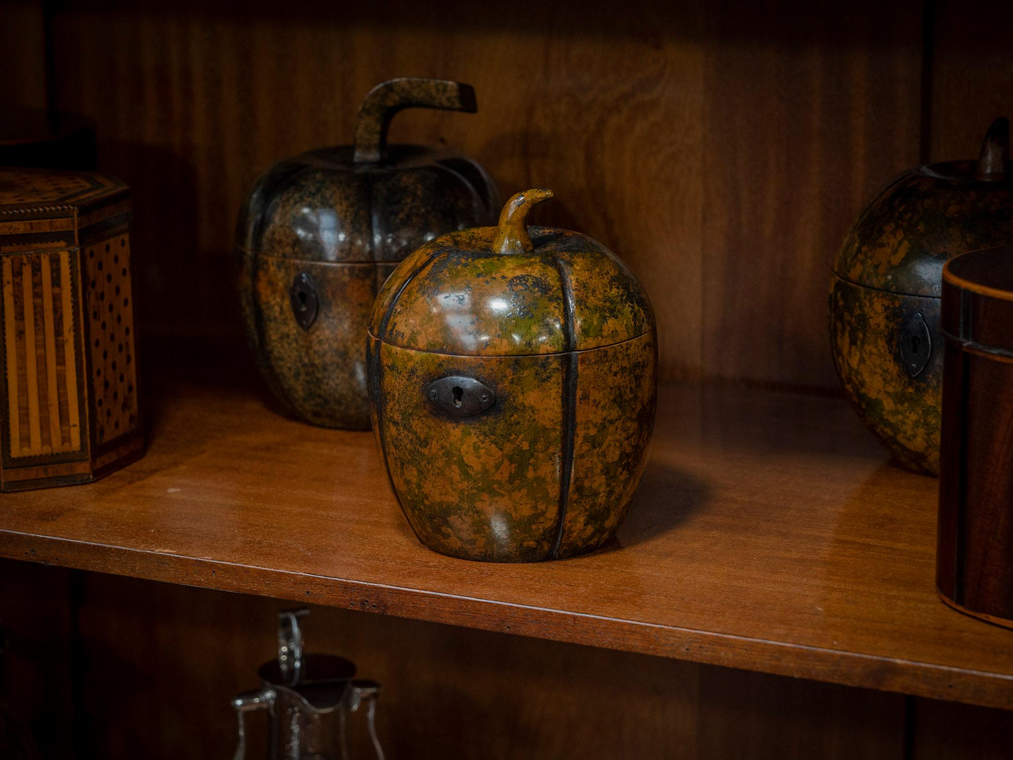 Die Teedose ist ein außergewöhnliches Exemplar in Form einer Melone und aus Sycamore mit einer schönen gesprenkelten Patinierung, die Farben von Moosgrün und dezentem Orange zeigt. Die Teedose wird von einem geschwungenen, naturalistischen Endstück