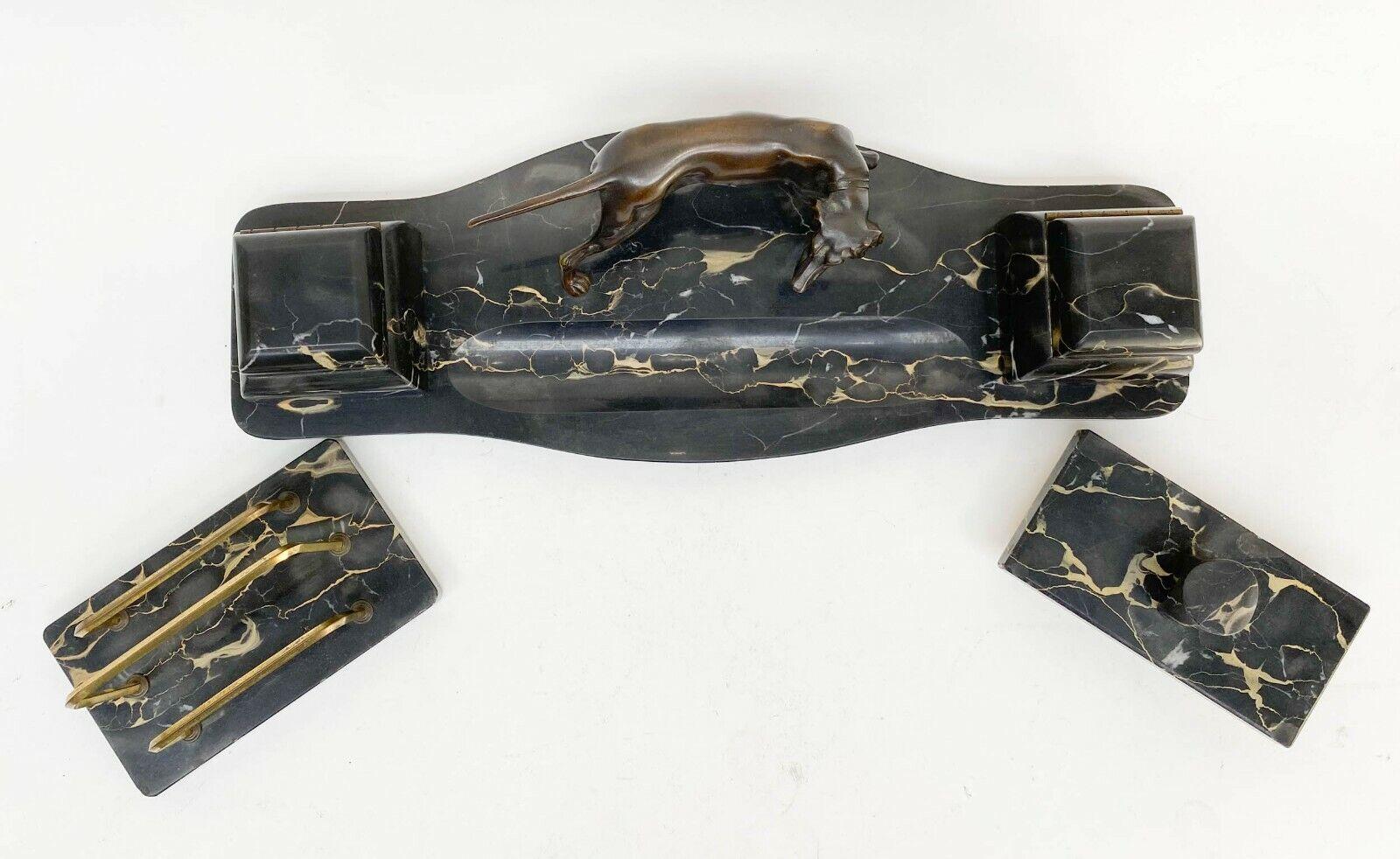 Continental Art Deco Bronze and Black Portor Marble Desk Set, circa 1925

Continental, likely German set includes a double inkwell/pen tray with patinated bronze hunting dog with glass liners in inkwells, an envelope holder with gilt bronze