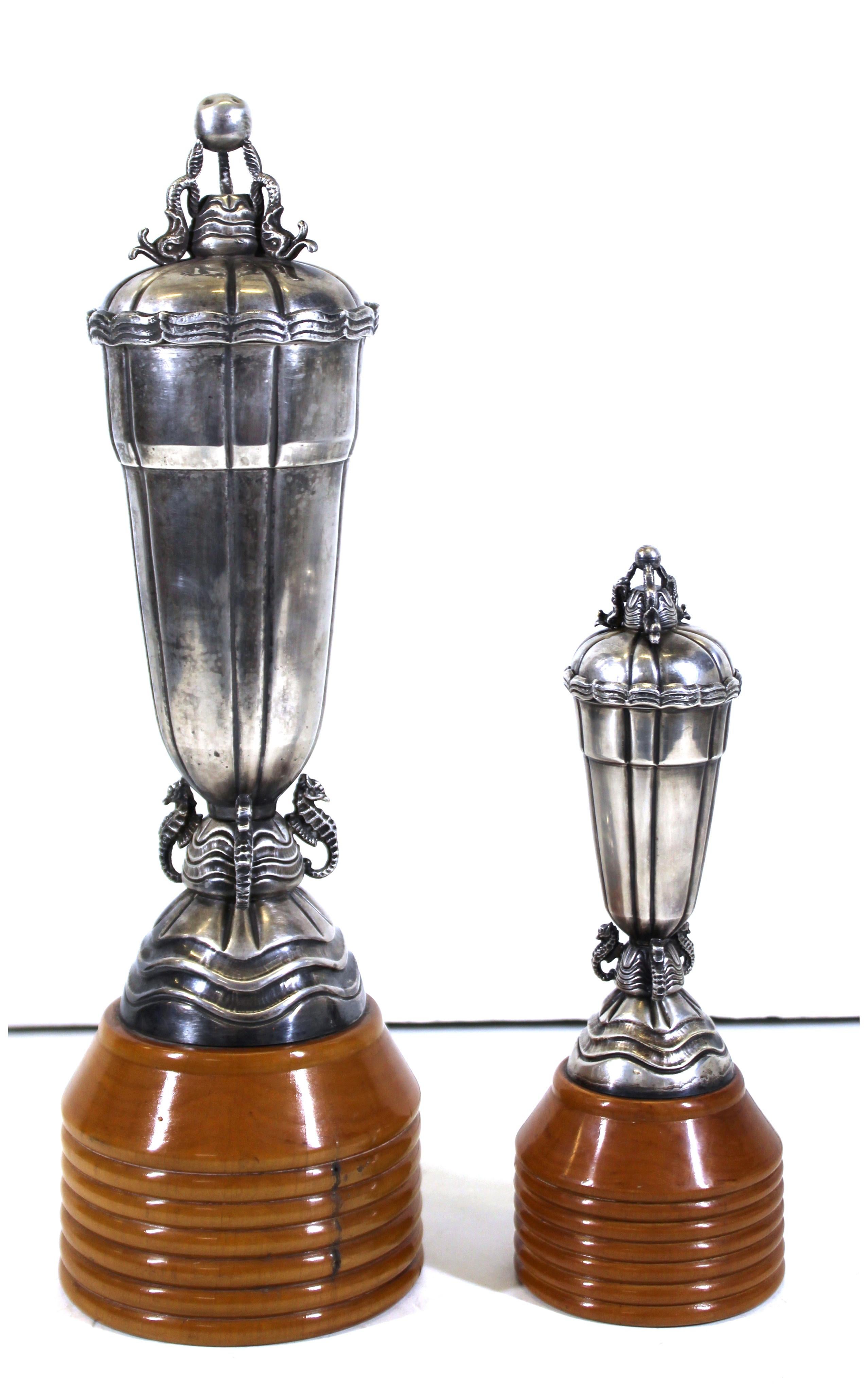 Continental Art Deco period pair of sterling silver covered urns adorned with dolphins on the covers and seahorses at the bases, mounted on turned wood bases. The pair was made in the 1920s in Europe, likely in Italy. In remarkable antique condition