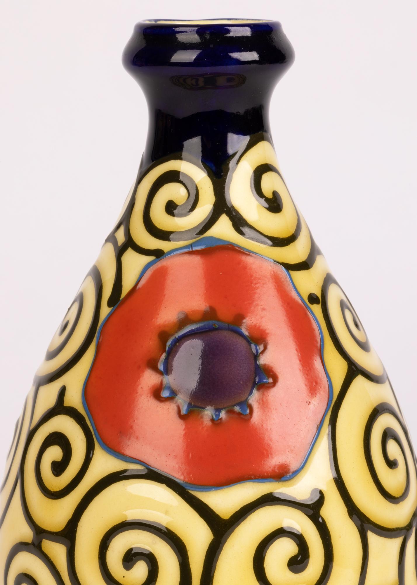 Un élégant vase en poterie d'art continentale, probablement autrichienne, Art déco, décoré de poppies serties dans un motif de volutes avec doublure de tubes. Le vase en forme de poire légèrement potée repose sur un étroit pied rond non émaillé avec