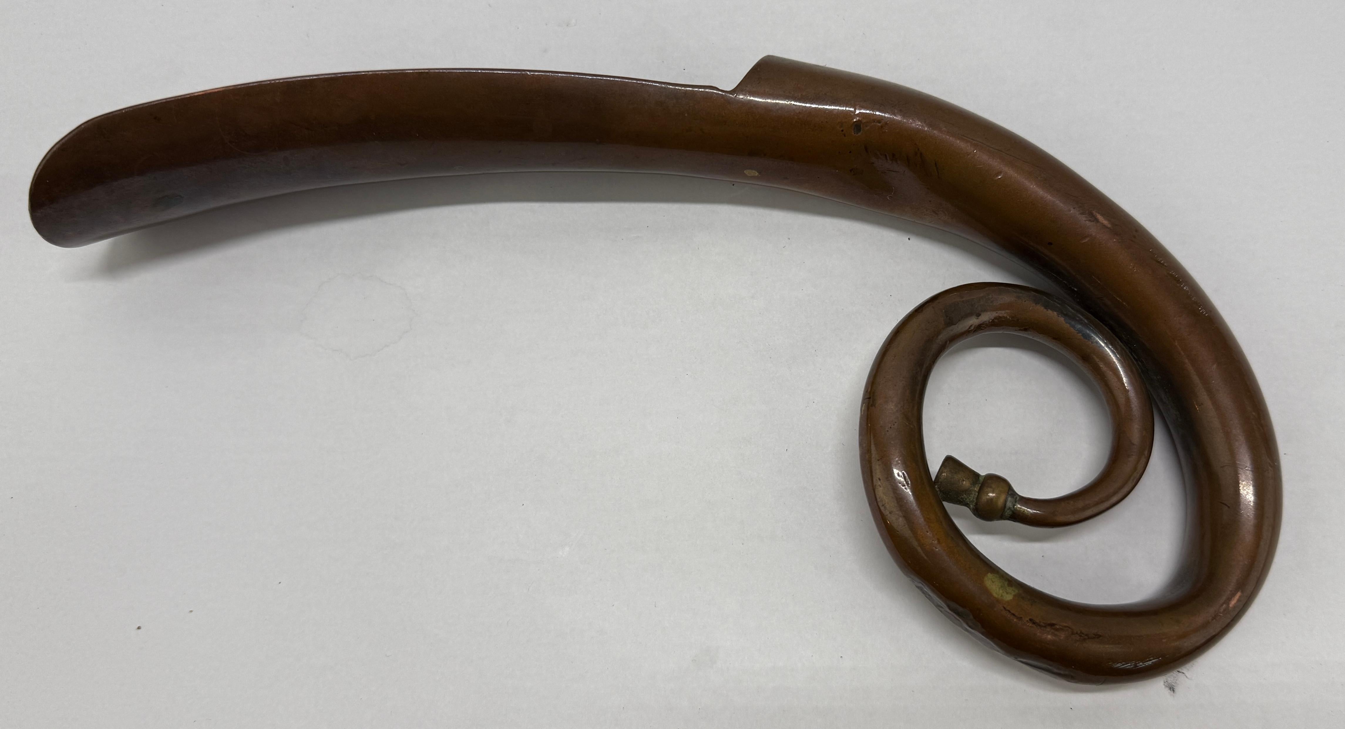 This handsome Continental Art Nouveau **bronze** shoehorn (c. 1900) is conceived as a stylized hunting horn: the handle sweeps into a sinuous whiplash scroll that tightens to a small knopped volute, visually echoing the coiled tube and mouthpiece of