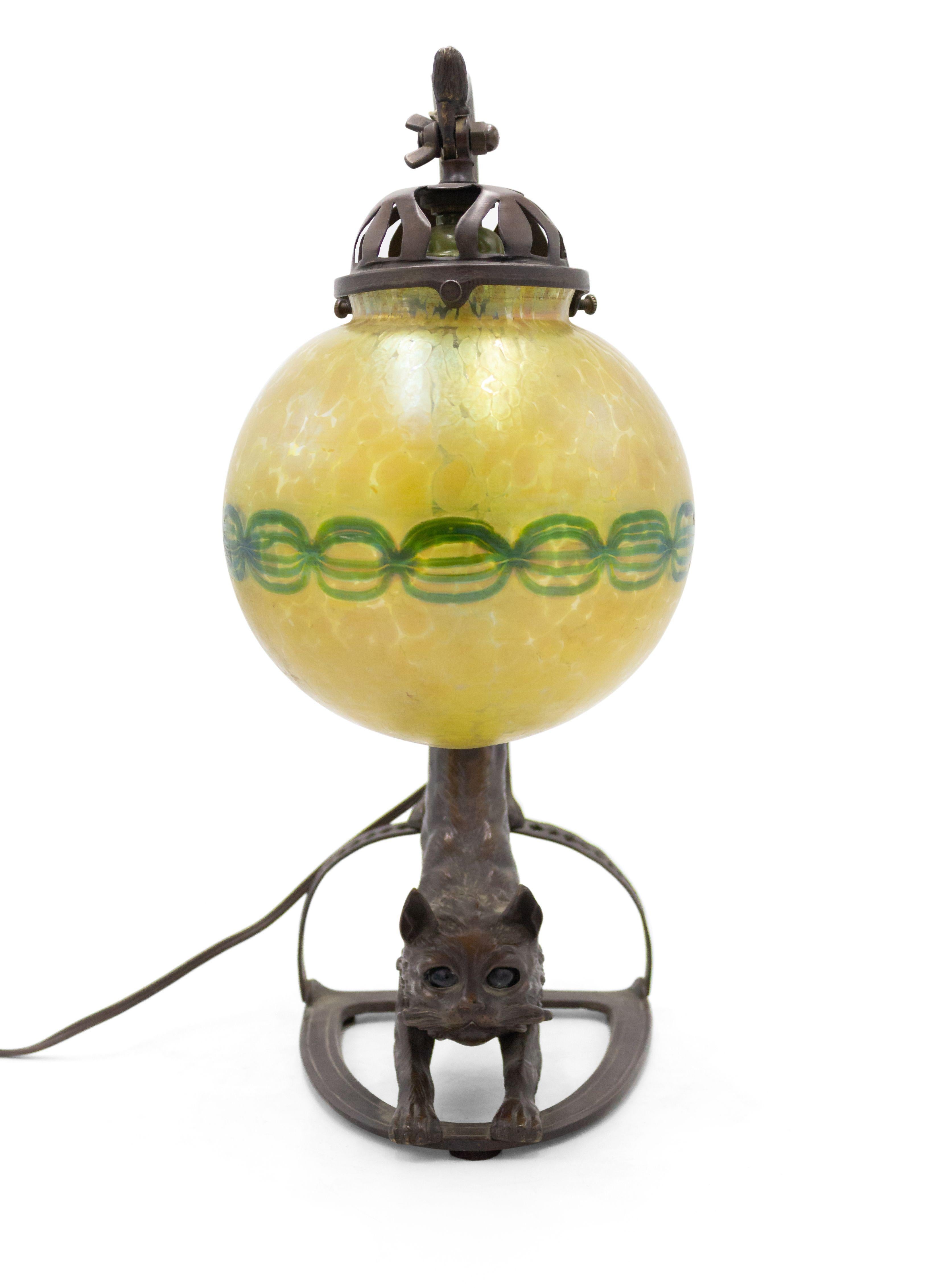 Continental Austrian style (20th Century) brown patina bronze lamp of rearing cat holding Loetz globe shade by tail.