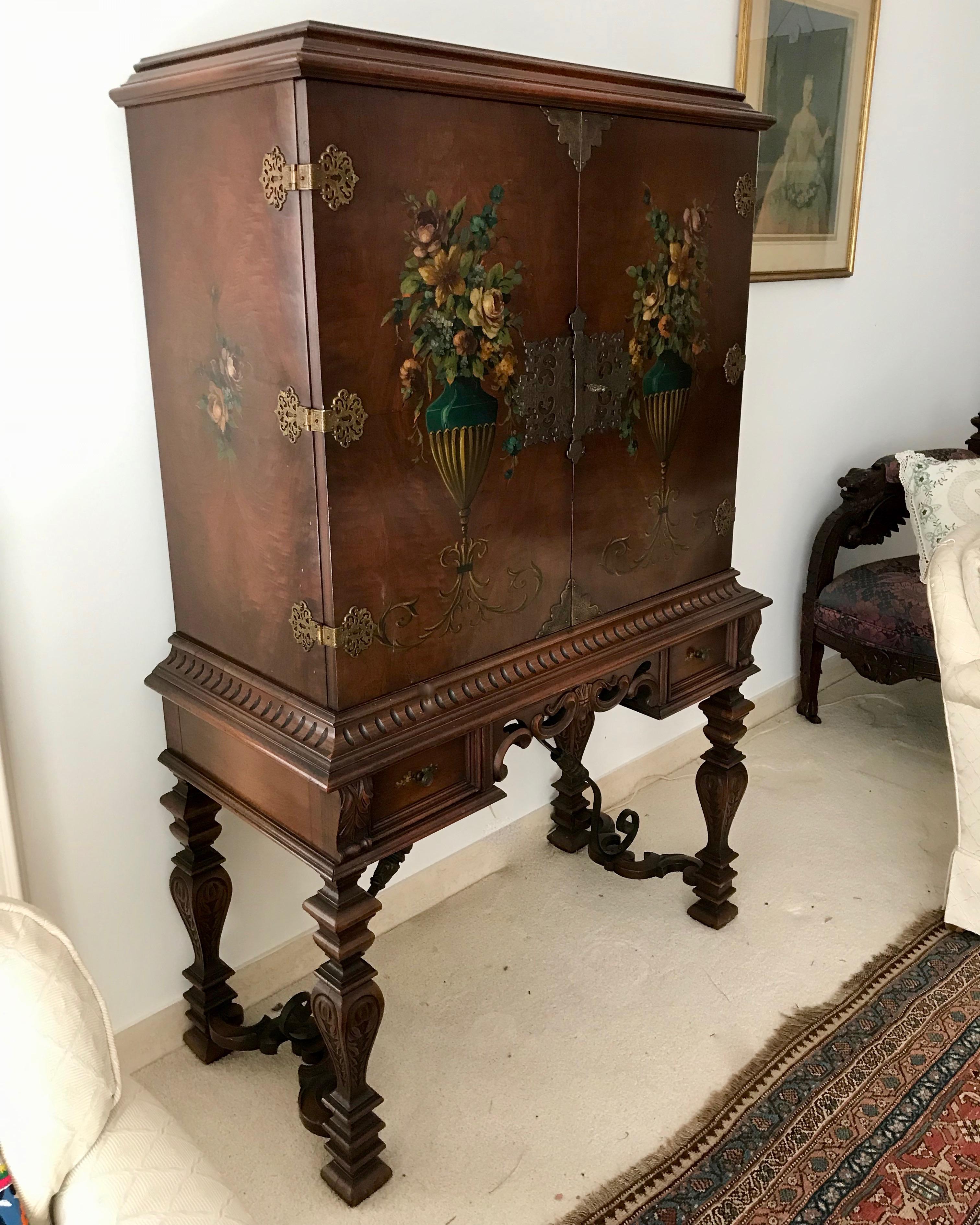 Highly decorative with hand painted urns adorning the 2 front doors -
which are richly appointed with elaborate hardware.
The cabinet is appointed with 2 drawers for holding bar accouterments -
corkscrews etc. The case is raised upon carved legs