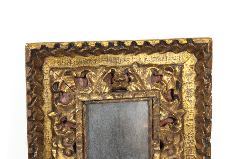 Continental Baroque giltwood frame with heavily carved foliage and red background color. Likely made in Europe in the early 19th century, the piece comes with an antique mirror insert. In great antique condition with age-appropriate wear and use.