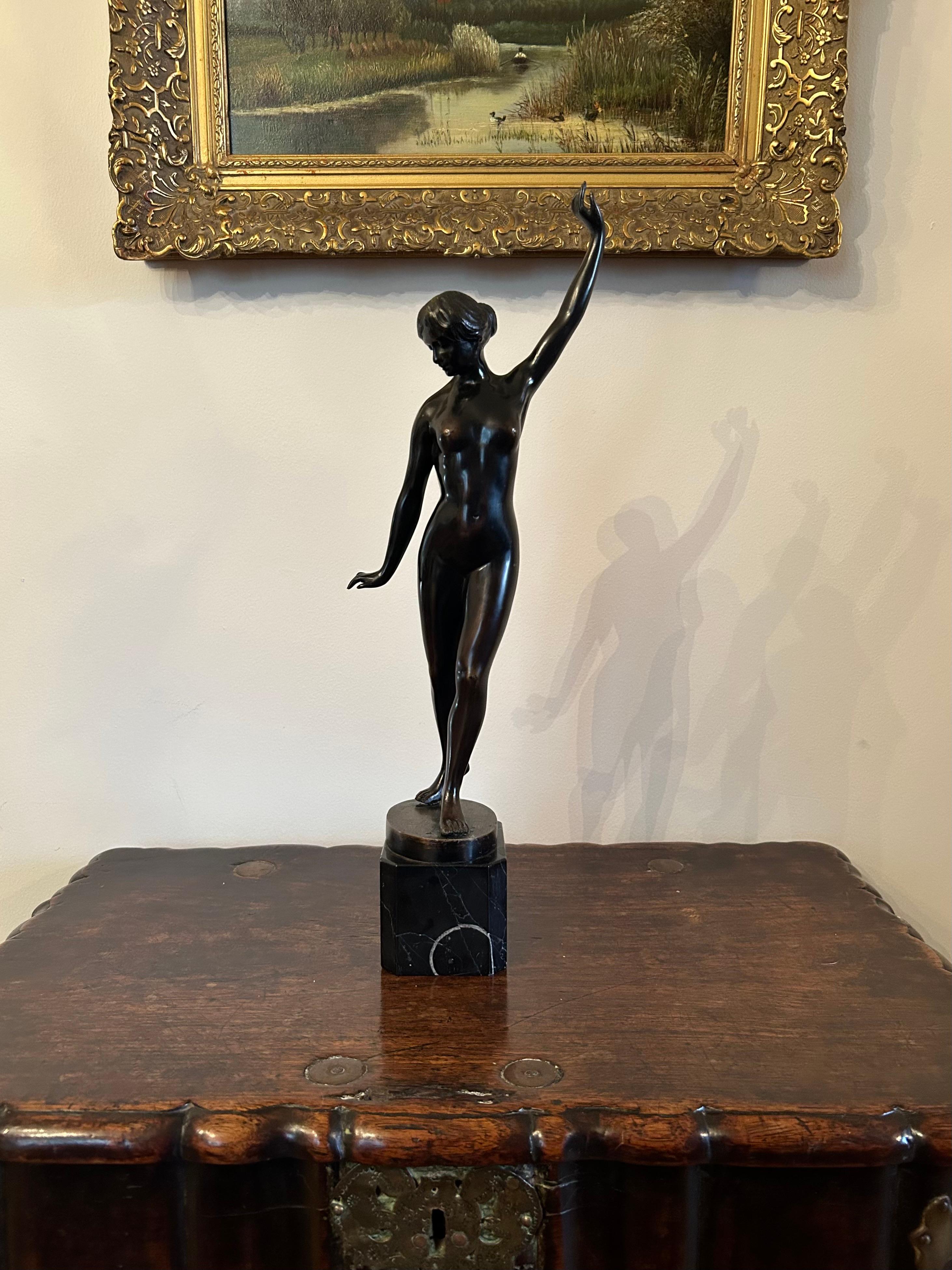 A beautiful continental bronze figure of a standing female on a black marble base. Early 20th century, signed illegibly on the base.
This elegant bronze has a wonderful patina and movement, as if the figure is about to step out into the world. 
Tiny