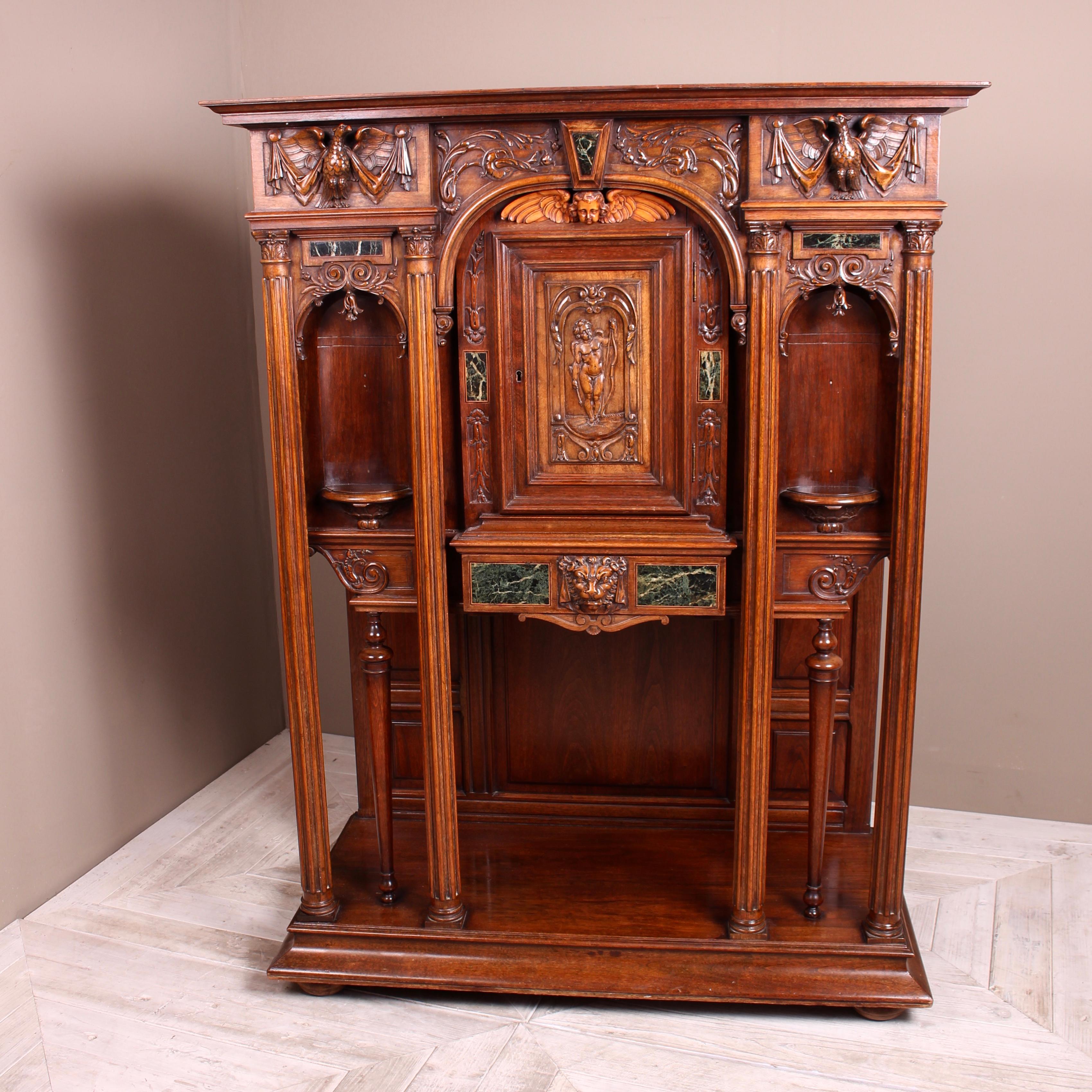 A fine continental carved walnut and marble ecclesiastical cabinet, circa 1890. A beautiful statement piece in heavily carved walnut and inset marble panels. The upper cornice with central floral and marble decoration flanked by classical phoenix