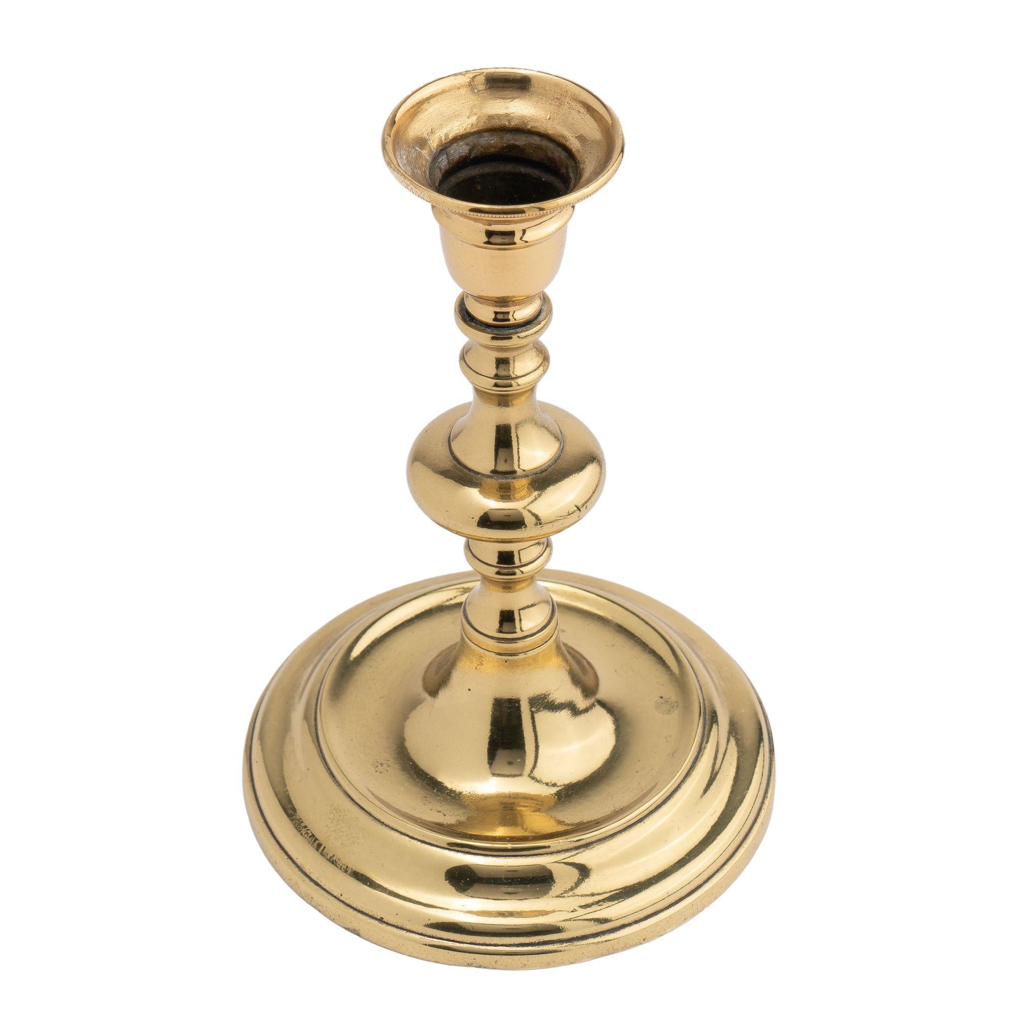 Cast brass candlestick with a circular base with drip pan on a stepped and domed base. The candlestick shaft is centered on a suppressed ball knob between similar waisted turnings. The shaft and base are joined by a hand threaded screw.
Continental,