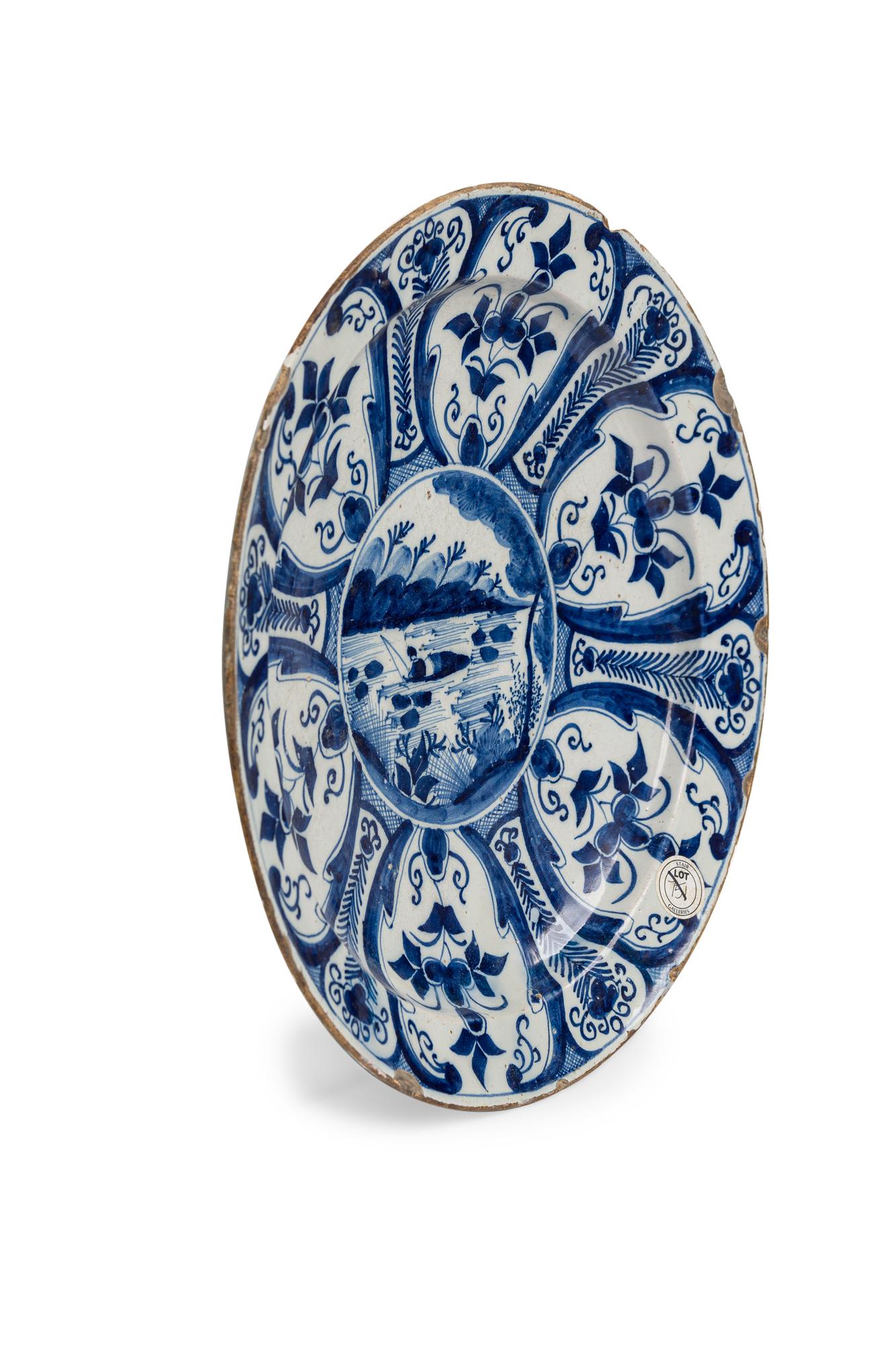 Continental Dutch (18th Century) blue and white decorated charger / plate with a centered scene of a person on a lake fishing surrounded by floral patterns