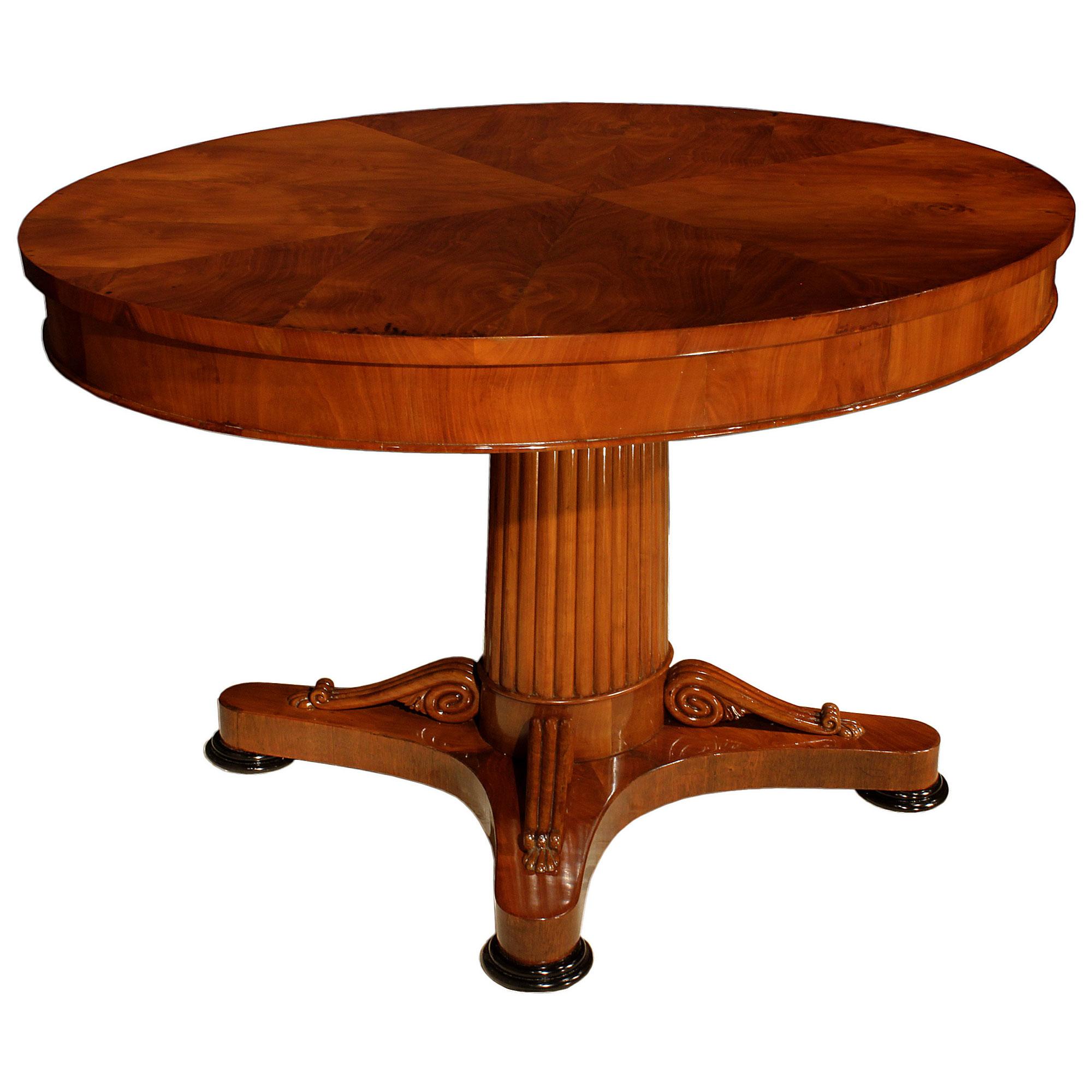 A striking Continental early 19th century mahogany center table. The table is raised on ebonized fruitwood feet below the concave sided stretcher decorated with scrolled elements topped with acanthus leaves. Above is the elegant reeded central