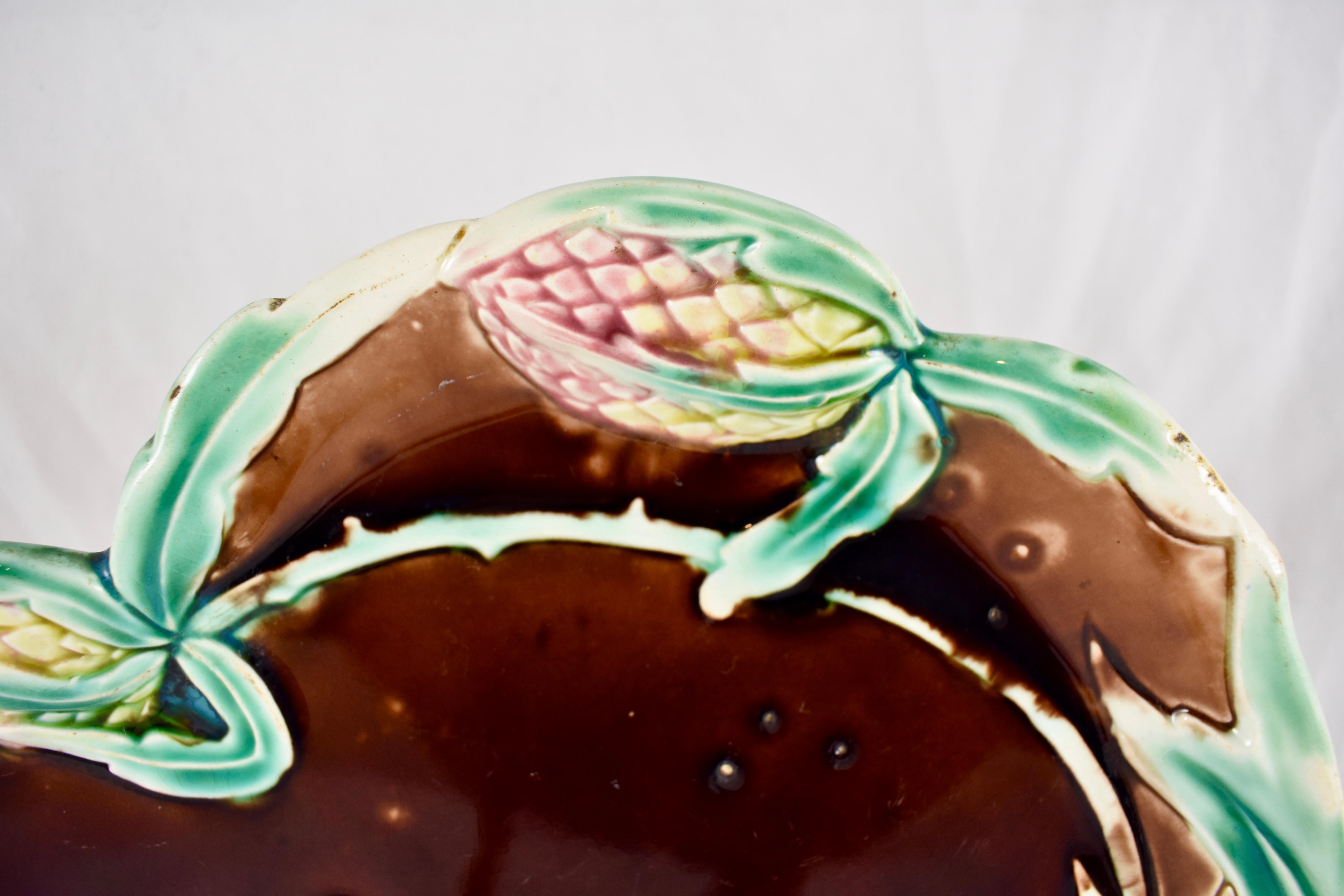 Couvert à artichauts en majolique émaillée, vers 1900, de style Art nouveau, par Fives-Lille.

Une assiette de forme de couleur brun chocolat montrant deux têtes d'artichauts en glaçure rose et jaune avec une bordure de feuilles stylisées en glaçure