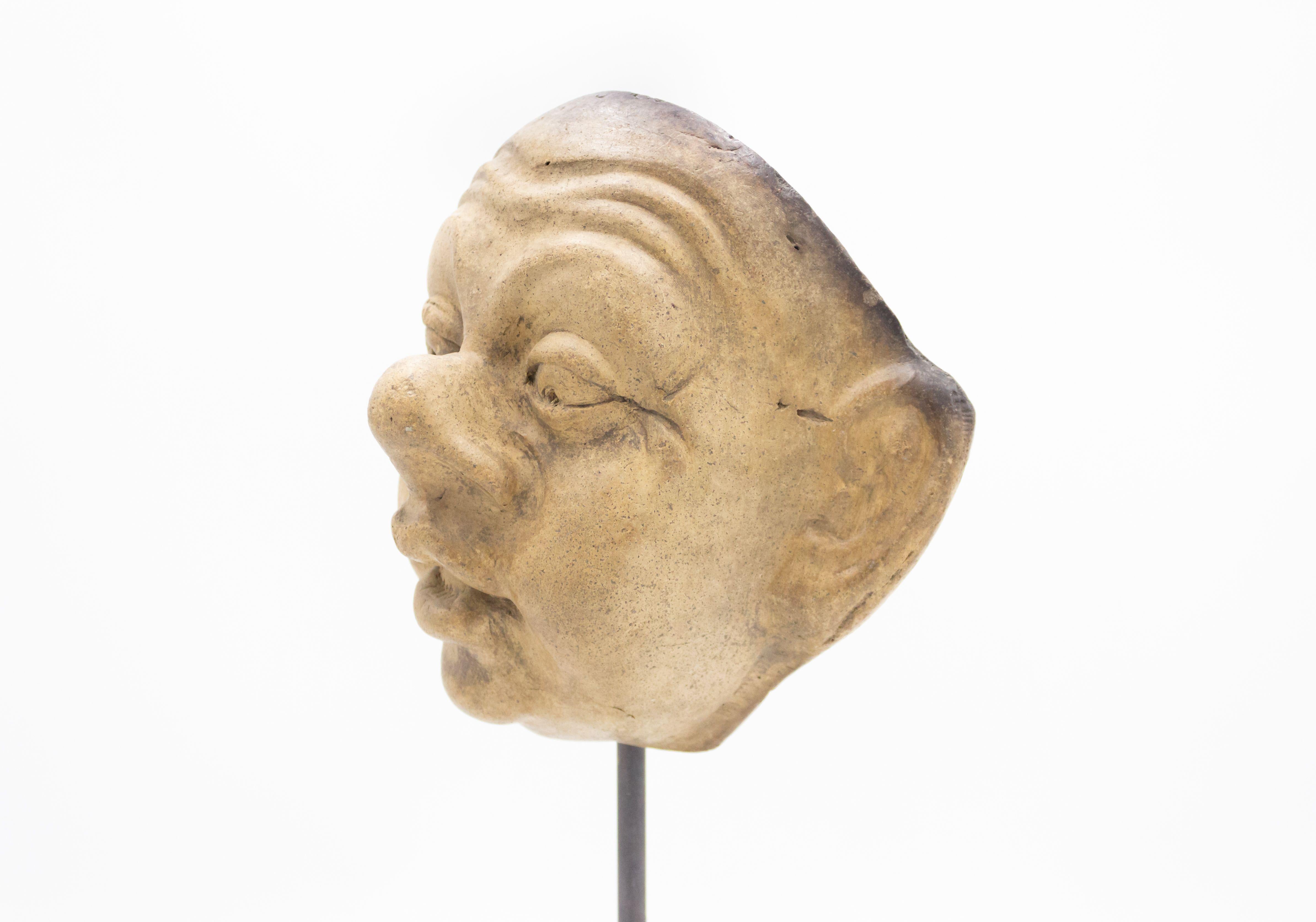 Kontinentaldeutsche (spätes 19. Jh.) Terrakotta-Maskenform eines überrascht dreinblickenden grotesken Gesichts mit großen Ohren und Nase auf einem quadratischen schwarzen Marmorsockel (Teil einer 39-teiligen Sammlung).
    