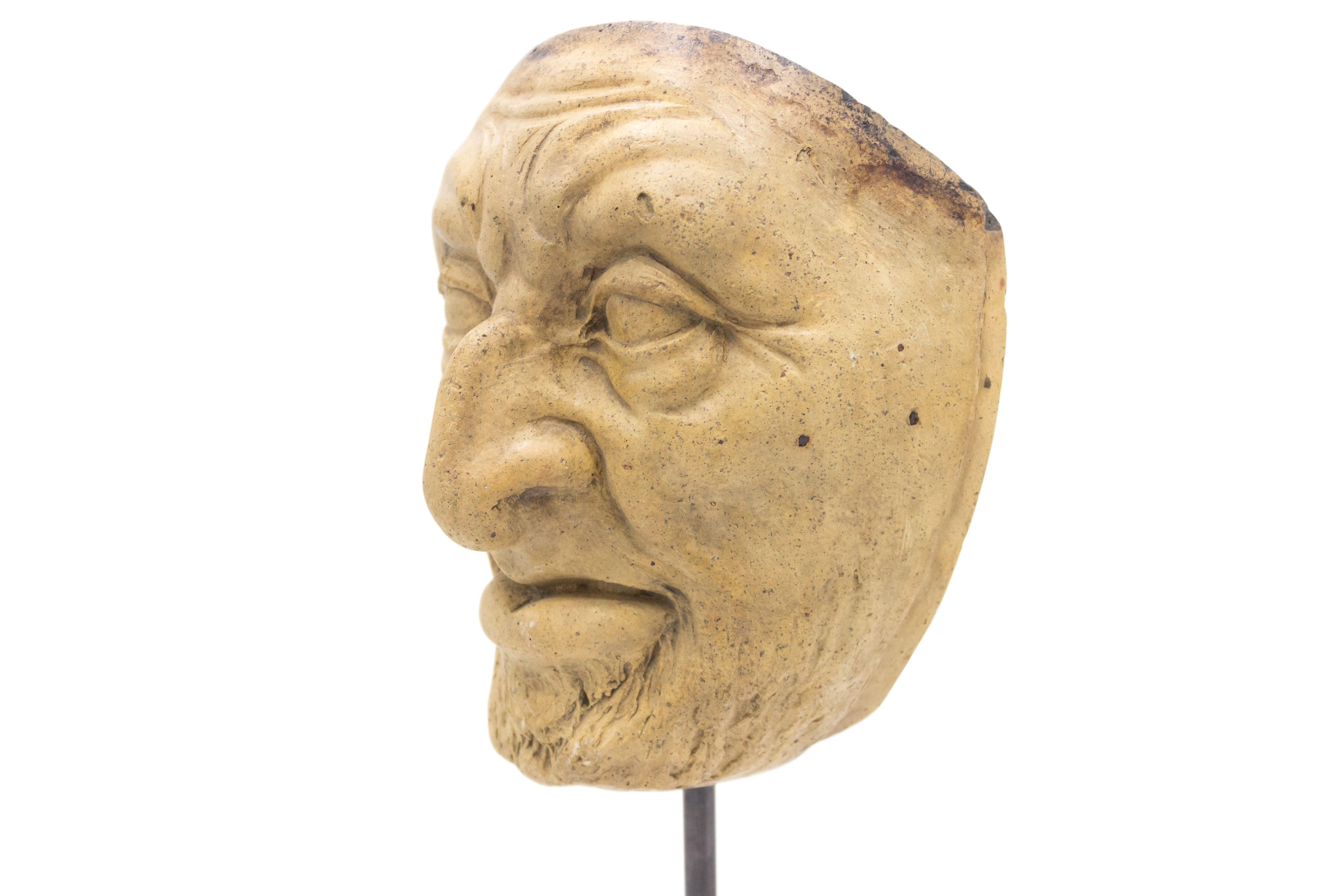 Continental German (late 19th Cent) sculpted terra-cotta master mask mold of a grimacing old man with a hooked nose & beard displayed on a square black marble base stand (part of a collection).
 