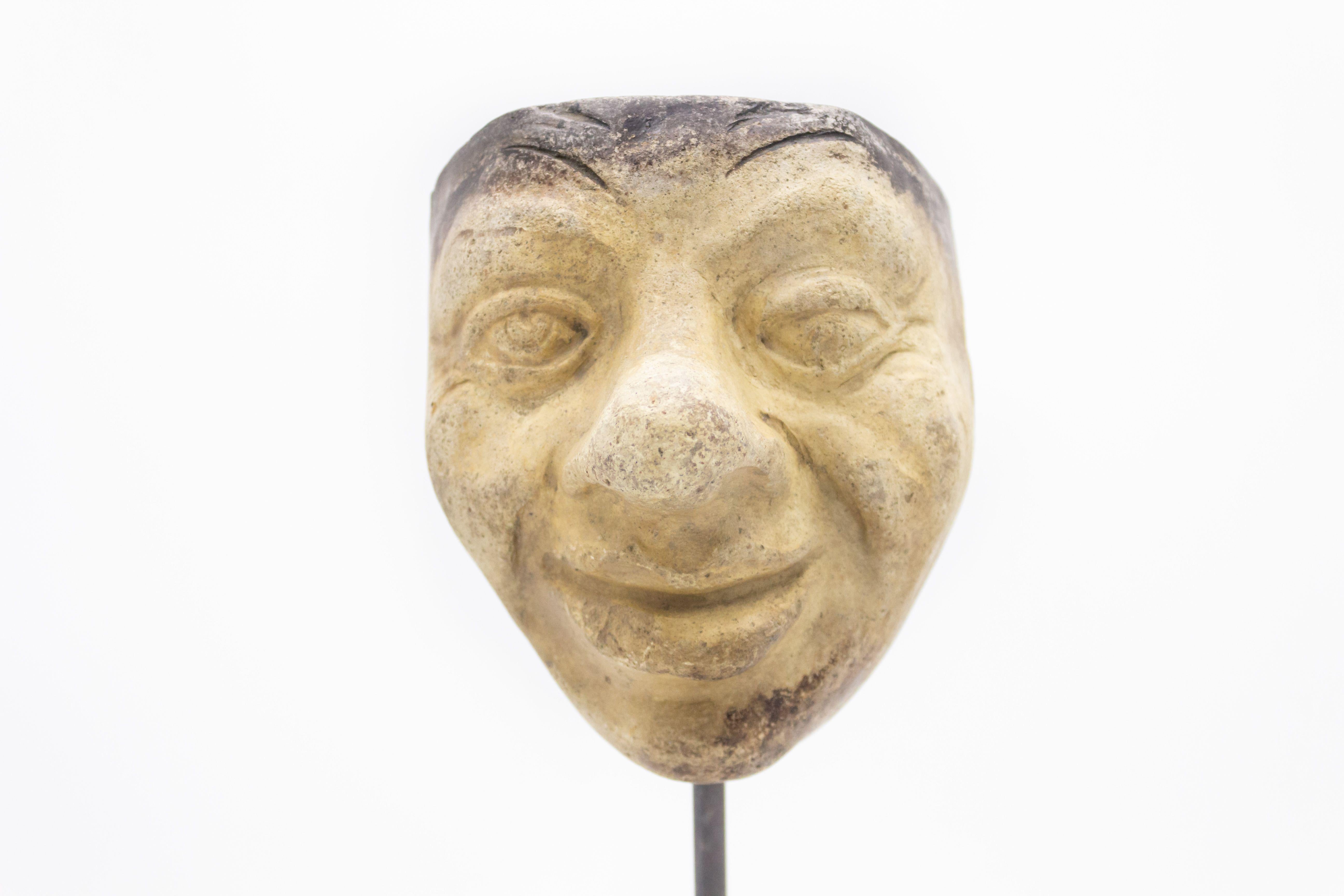 Kontinentaldeutsche (spätes 19. Jh.) Terrakotta-Maskenform eines lächelnden Groteskengesichts mit Knollennase auf einem quadratischen schwarzen Marmorsockel (Teil einer 39-teiligen Sammlung).
 
