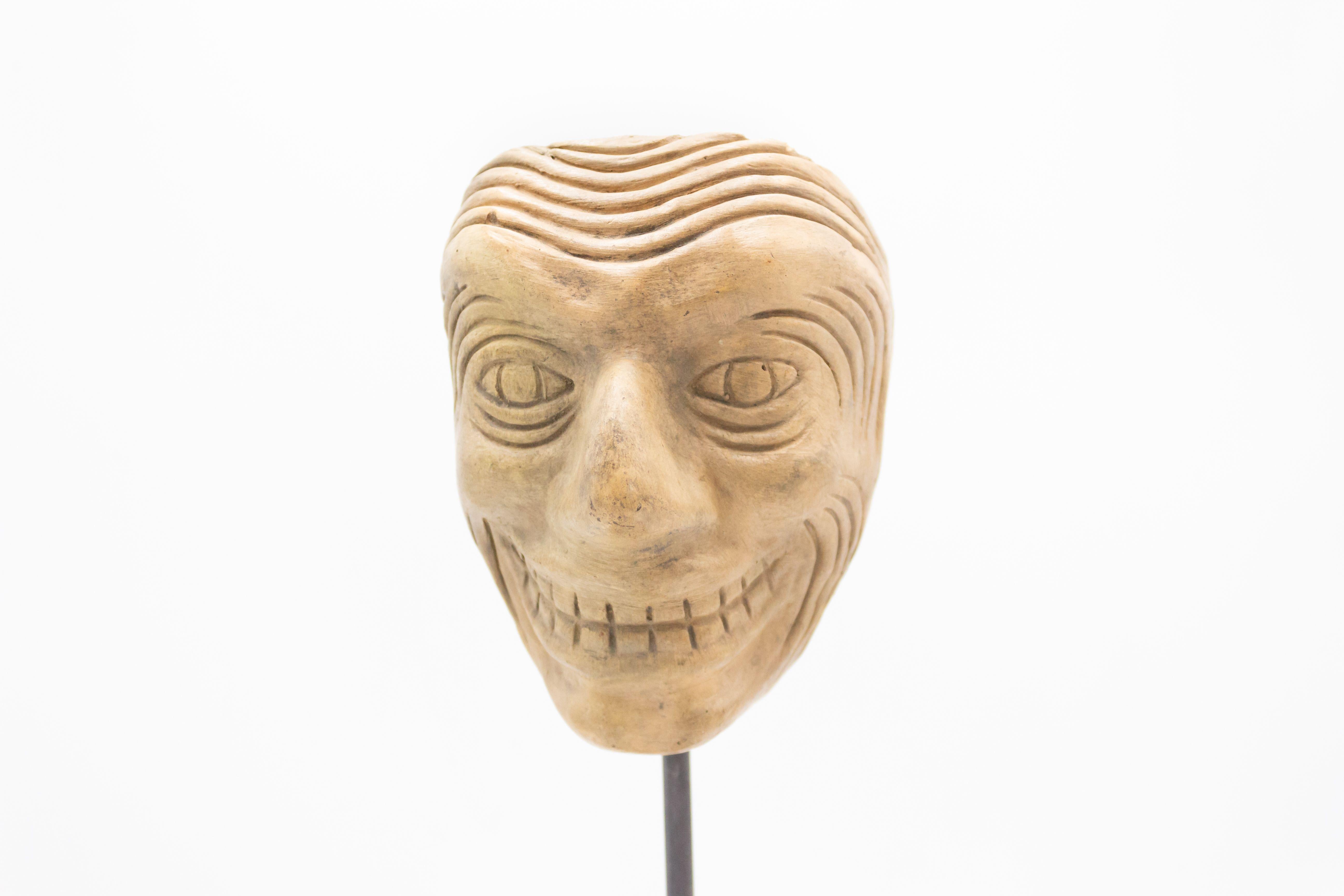 Continental German (late 19th cent) sculpted terra-cotta master mask mold of an insane looking Grotesque face with deep laugh lines displayed on a square black marble base stand (part of a 39 piece collection).
       