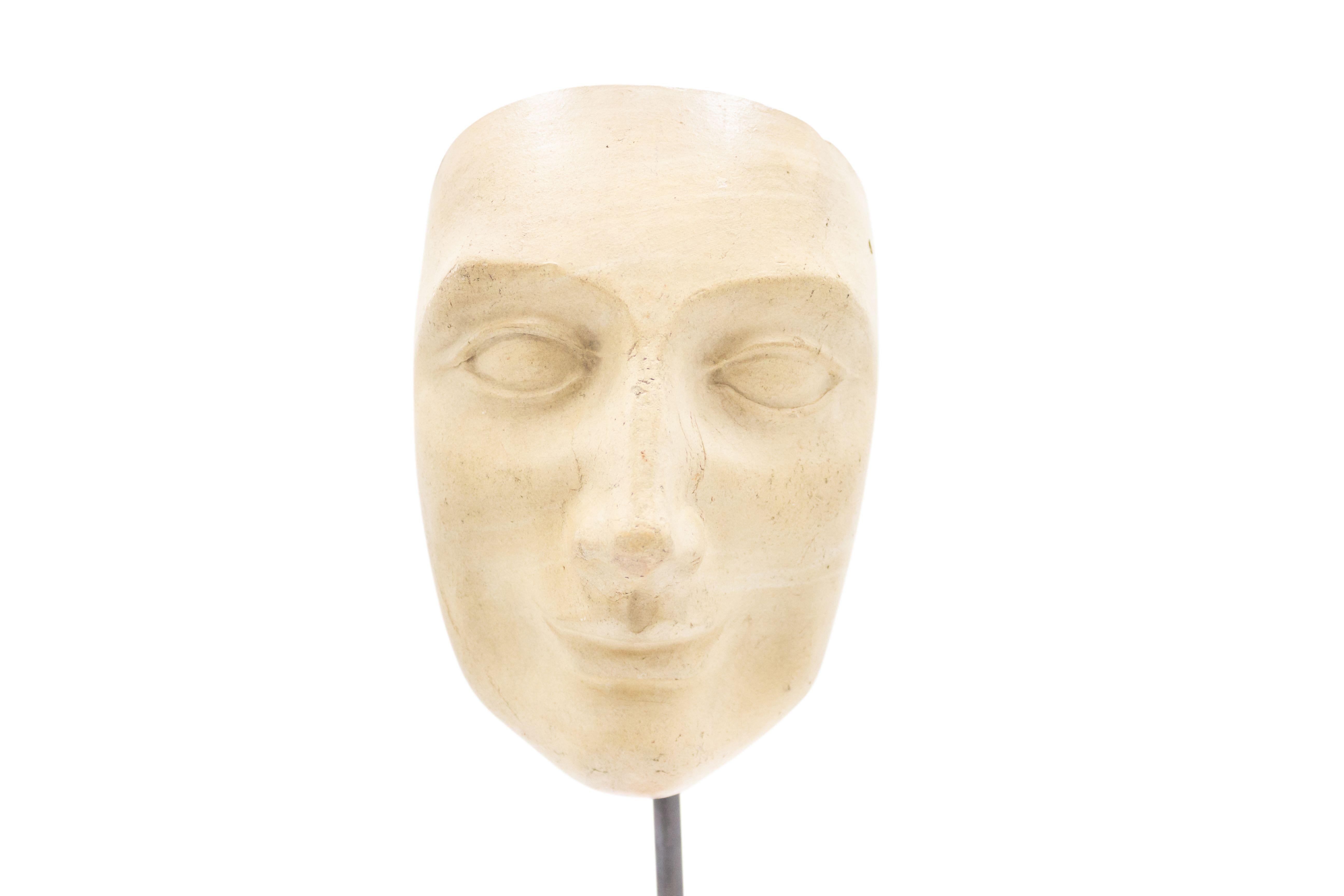 Continental German (late 19th Cent) sculpted terra-cotta master mask mold bust of a smiling serene face displayed on a square black marble base stand (part of a collection).
  