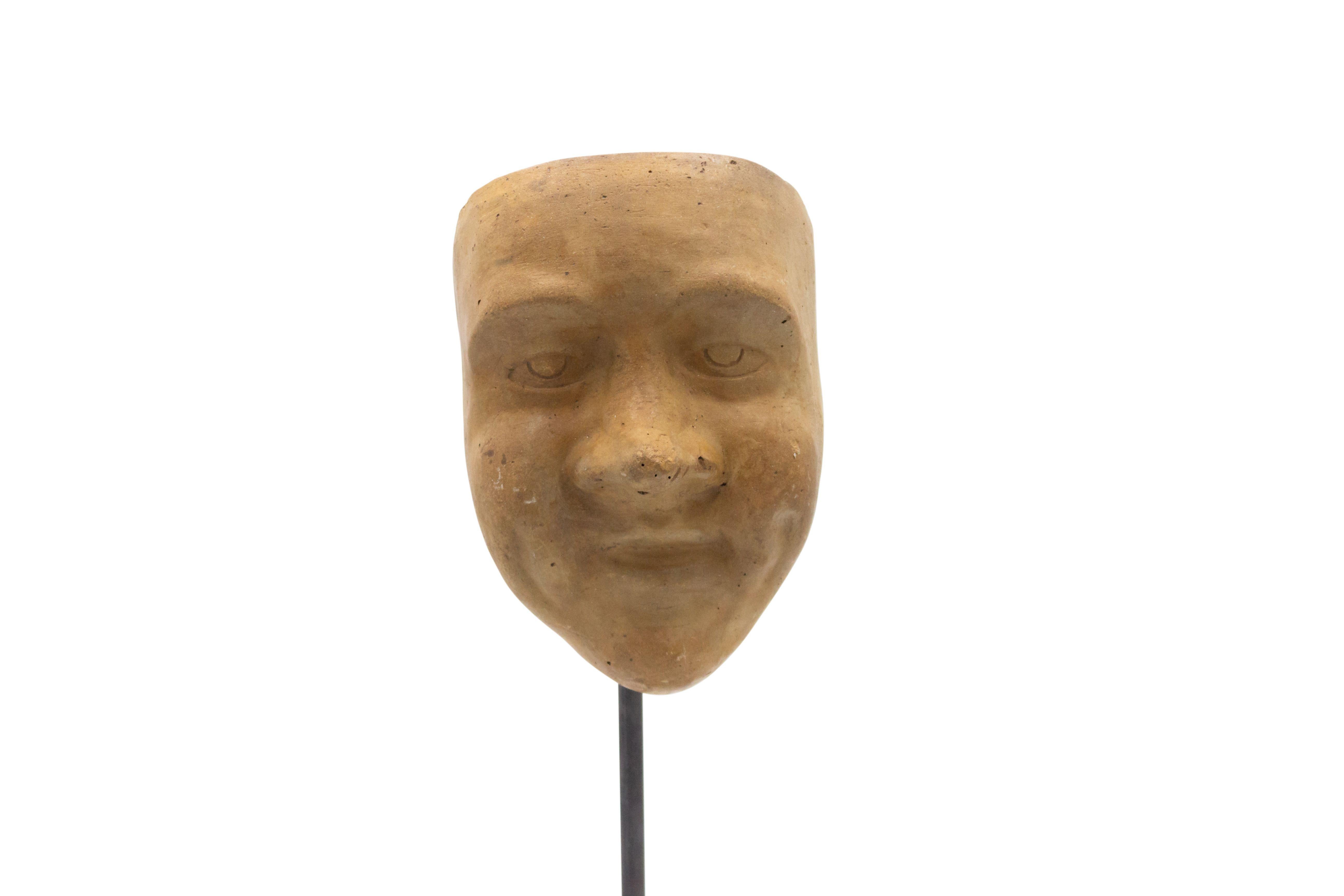 Continental German (late 19th Cent) sculpted terra-cotta master mask mold of a face with pudgy cheeks displayed on a square black marble base stand (part of a collection).
 