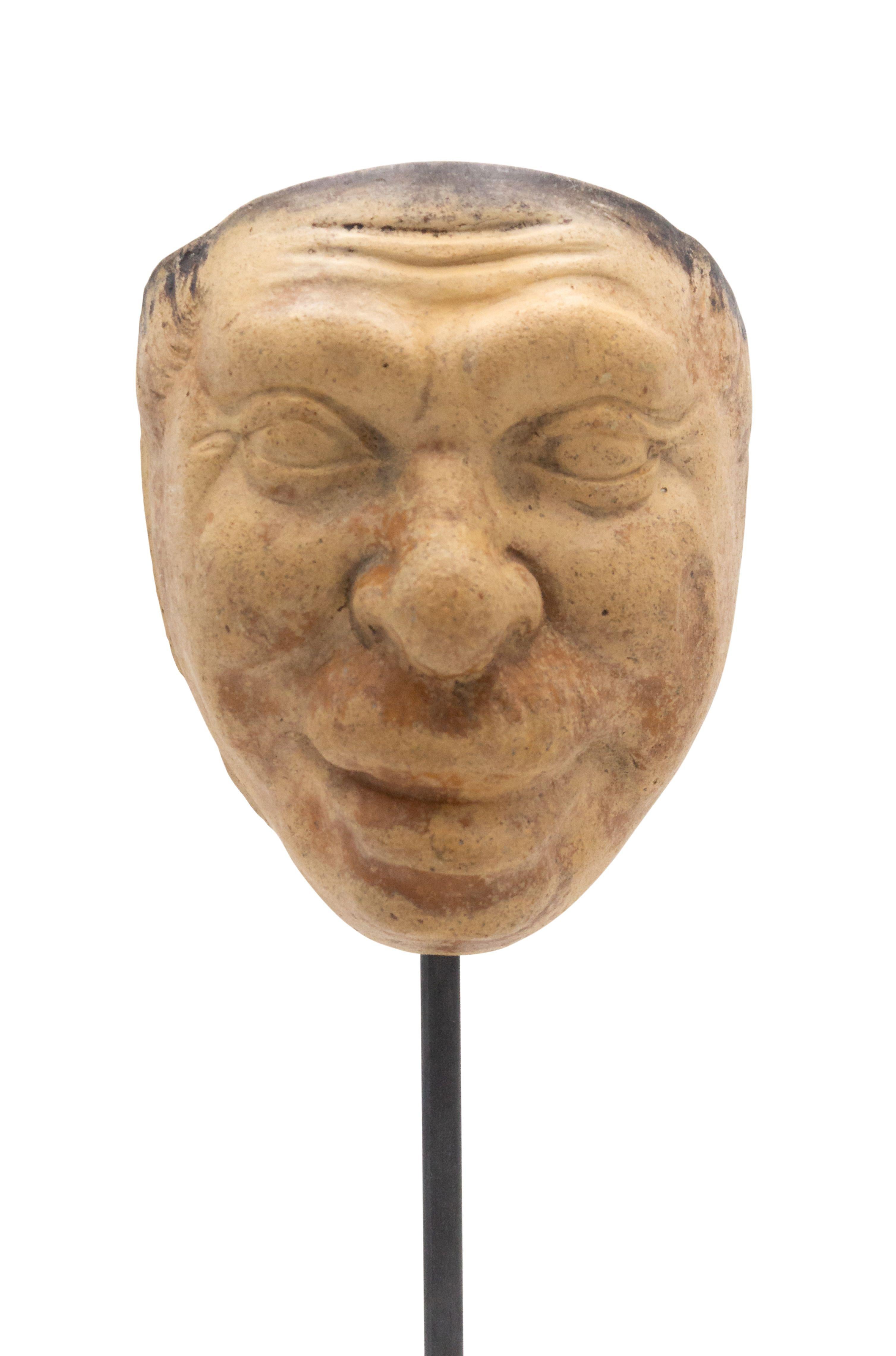 Continental German (late 19th Cent) sculpted terra-cotta master mask mold of a smiling Grotesque face with a mustache displayed on a square black marble base stand (part of 39 pc. Collection).
 
