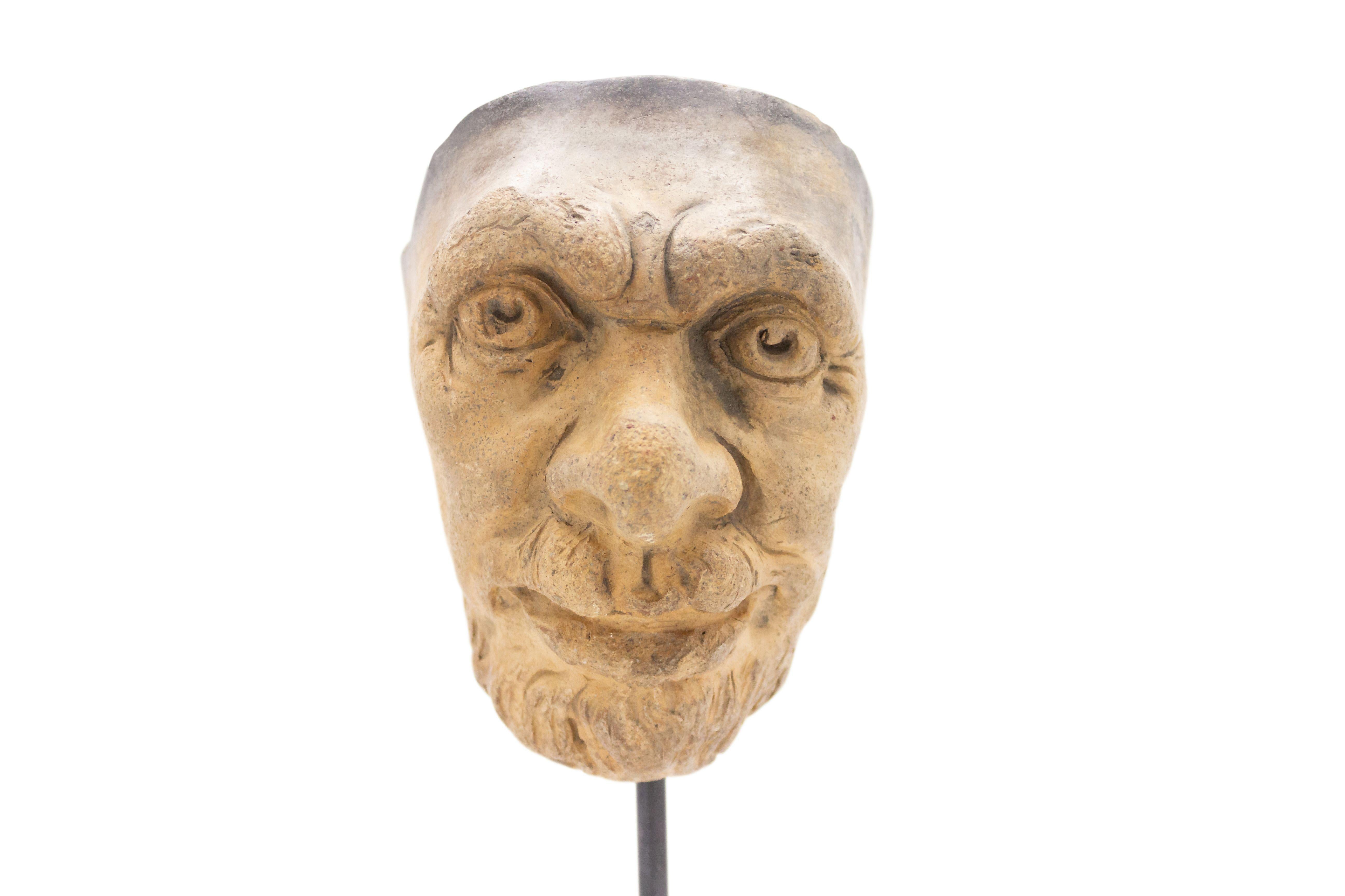 Continental German (late 19th Cent) sculpted terra-cotta master mask mold of a bearded old man with furrowed brow displayed on a square black marble base stand (part of a collection).
 