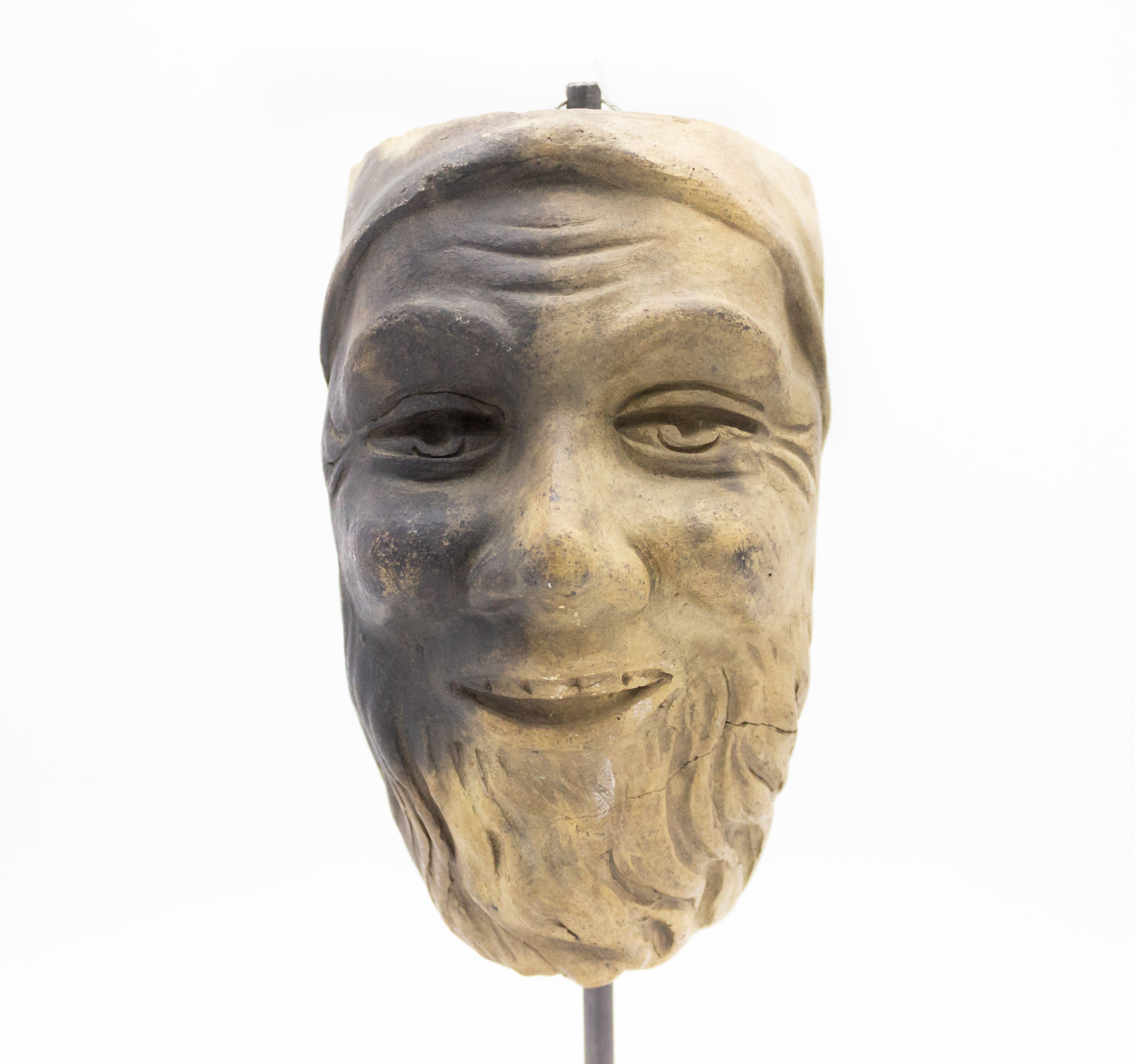 Continental German (late 19th cent) sculpted terra-cotta master mask mold of a smiling man with a beard and cap displayed on a square black marble base stand (part of a 39 piece collection).
     