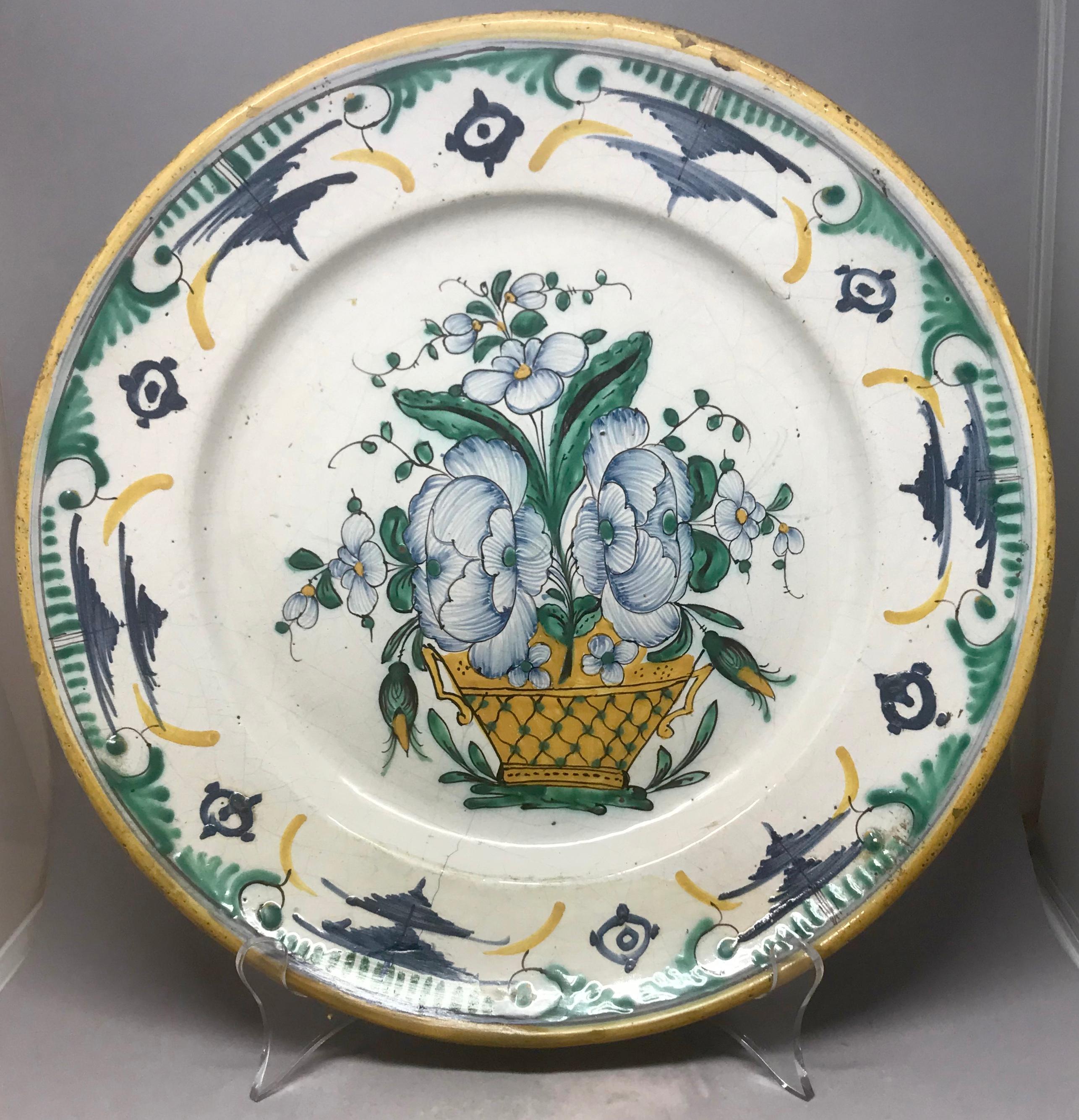 Green and yellow Continental Majolica plate. Large green, yellow, blue and white floral centered basket with mustard gold accents and rim. Probably Spain, 19th century. 
Dimensions: 12